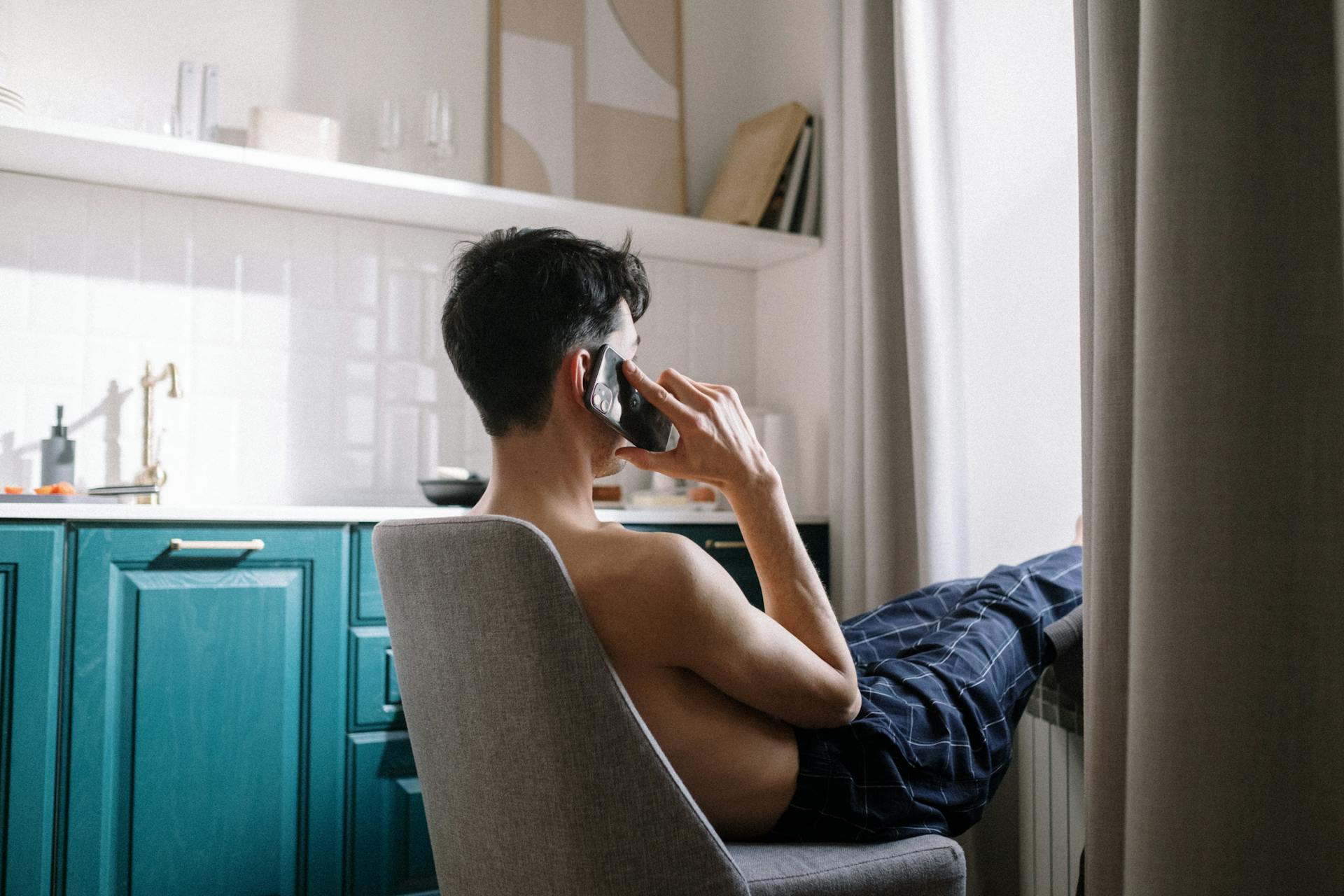 A side view shot of a man sitting on the chair and talking on his phone | Source: Pexels