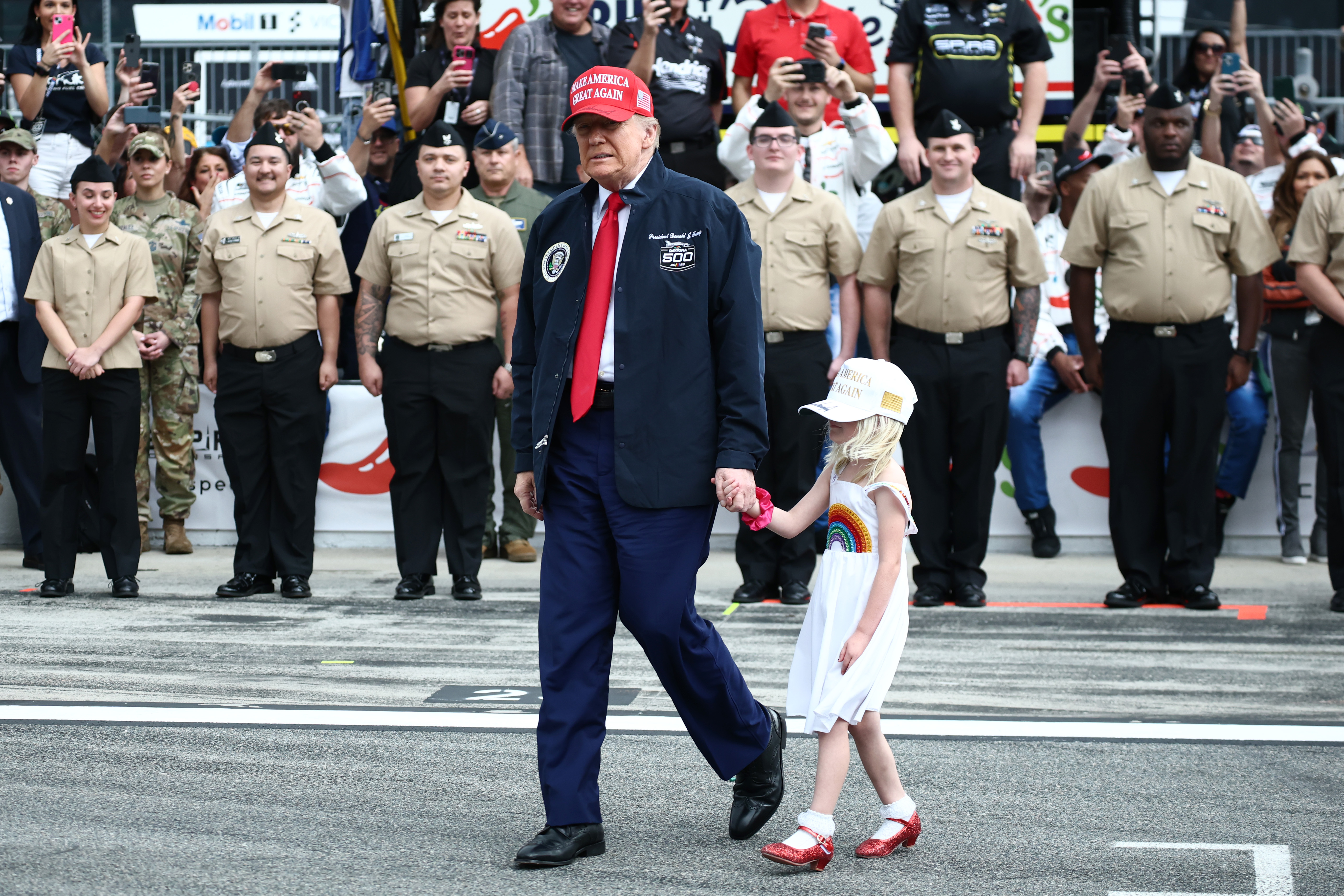 U.S. President Donald Trump and his granddaughter are pictured walking on the grid prior to the NASCAR Cup Series Daytona 500 at Daytona International Speedway on February 16, 2025, in Daytona Beach, Florida | Source: Getty Images