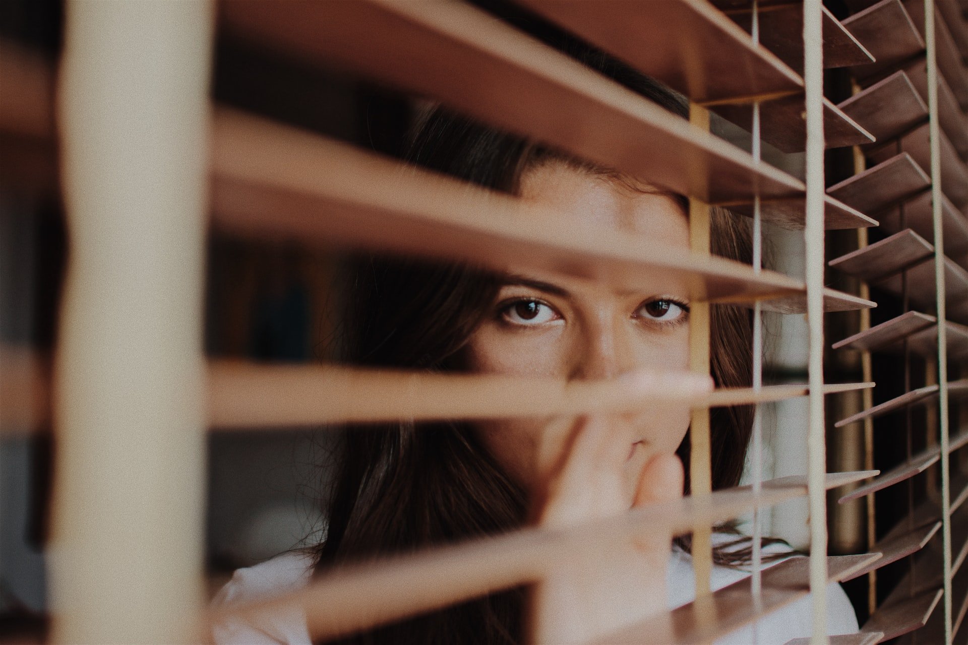 A woman looking through window blinds | Source: Unsplash