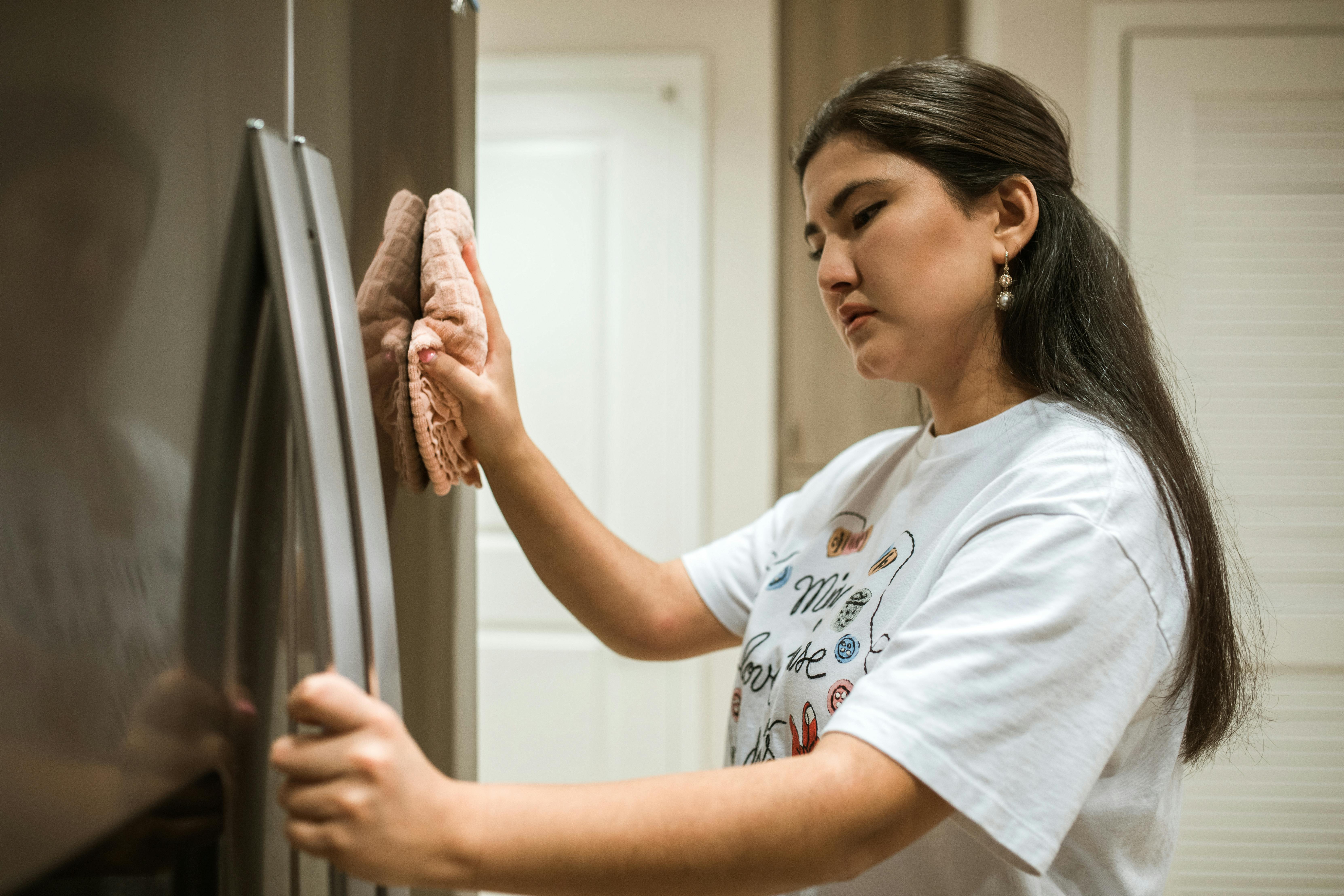 A woman cleaning a refrigerator. | Source: Pexels