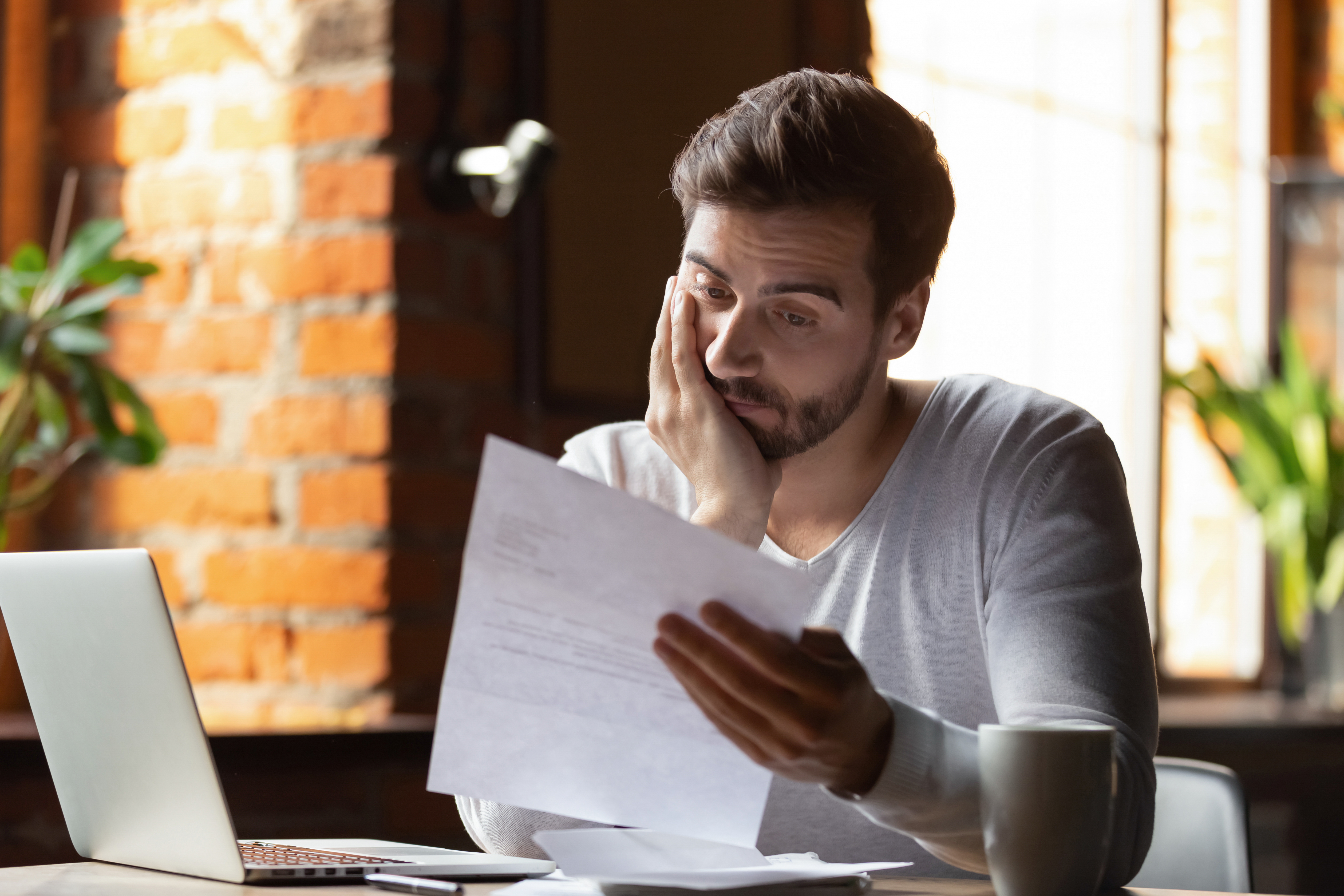 A confused and frustrated man reading some paper work | Source: Shutterstock