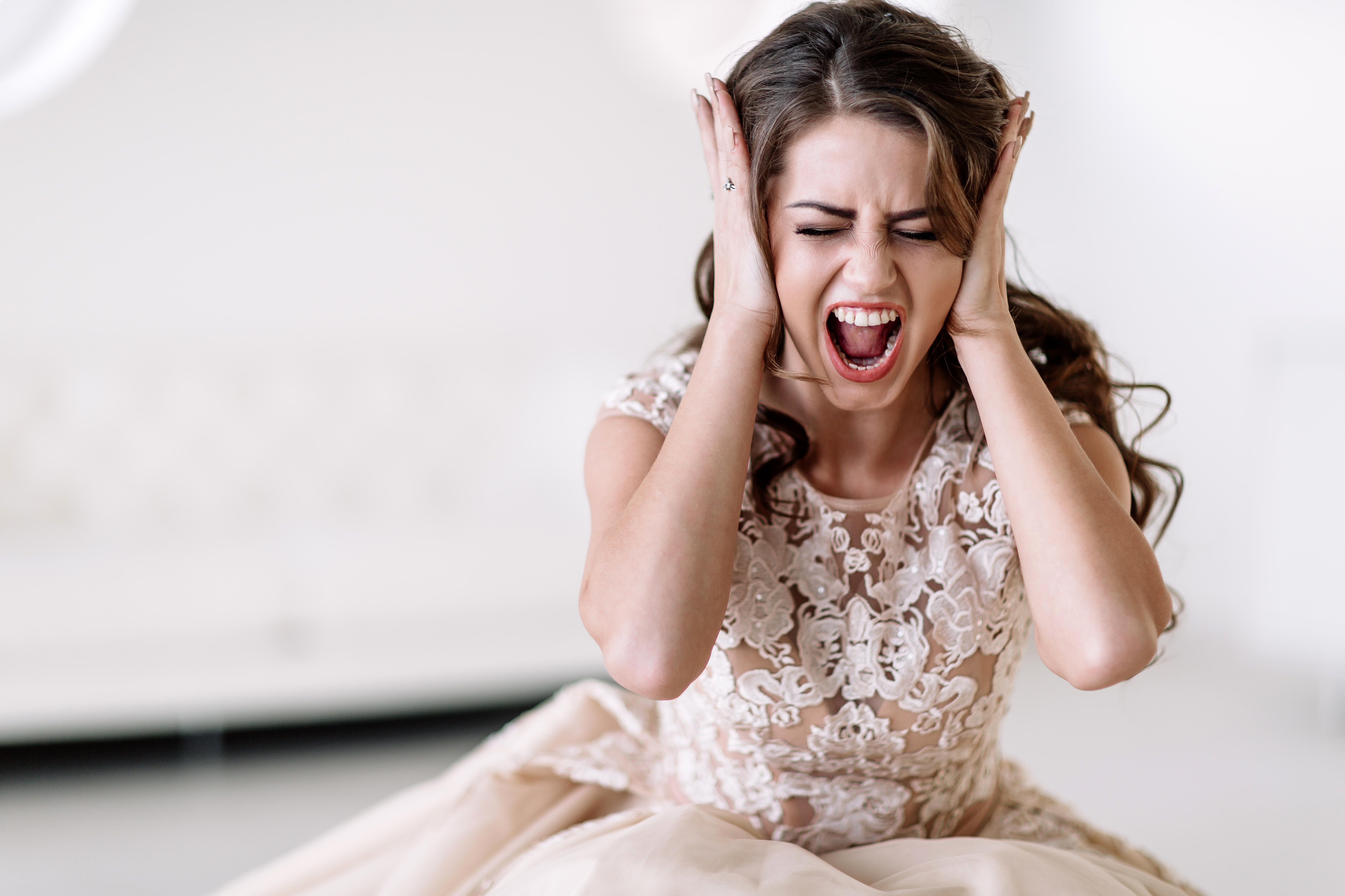 A bride screaming with her hands over her ears | Source: Shutterstock
