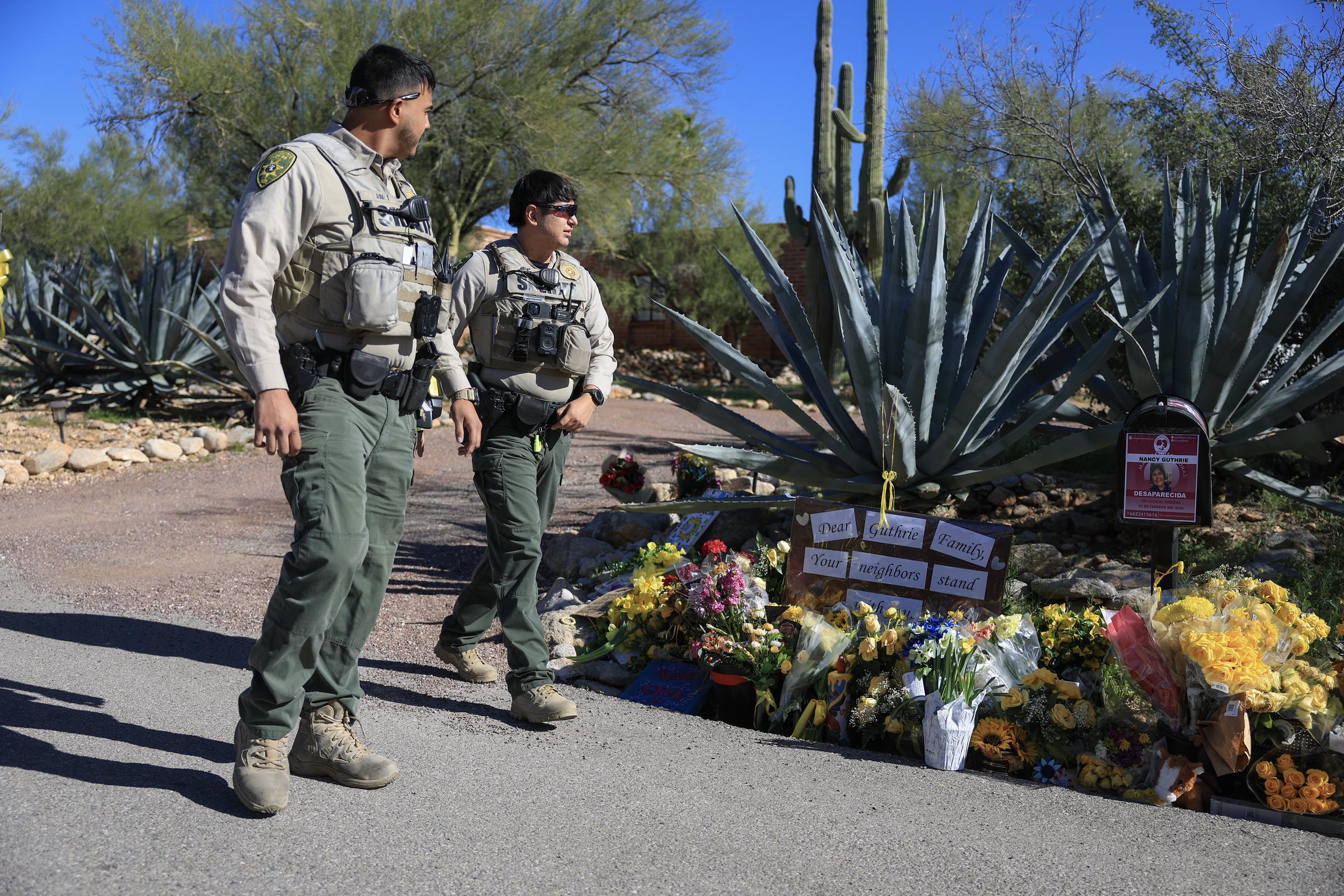 Pima County Sheriff deputies walk past a memorial outside Nancy Guthrie's home on February 22, 2026, in Tucson, Arizona | Source: Getty Images