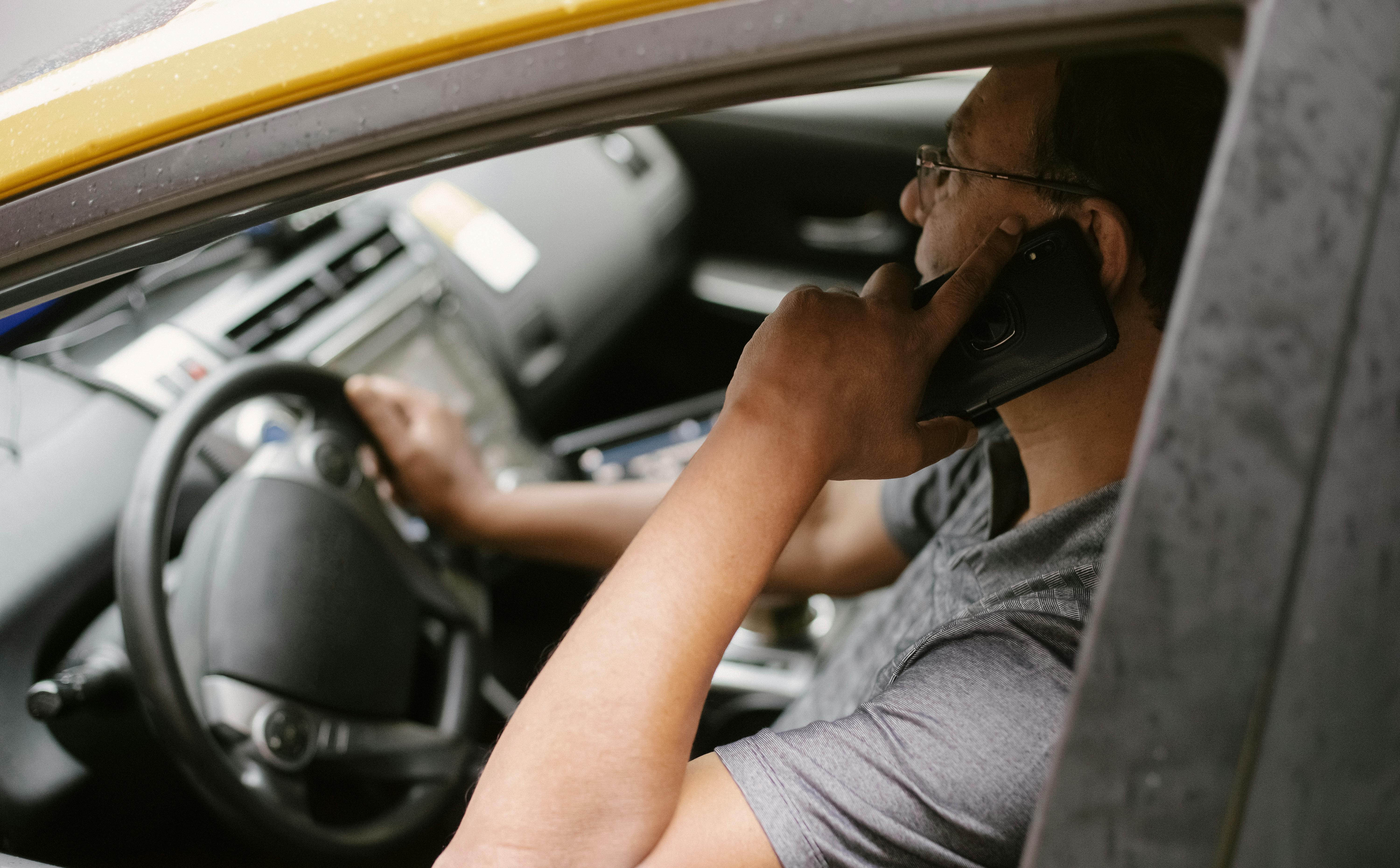Man using a phone while driving | Source: Pexels
