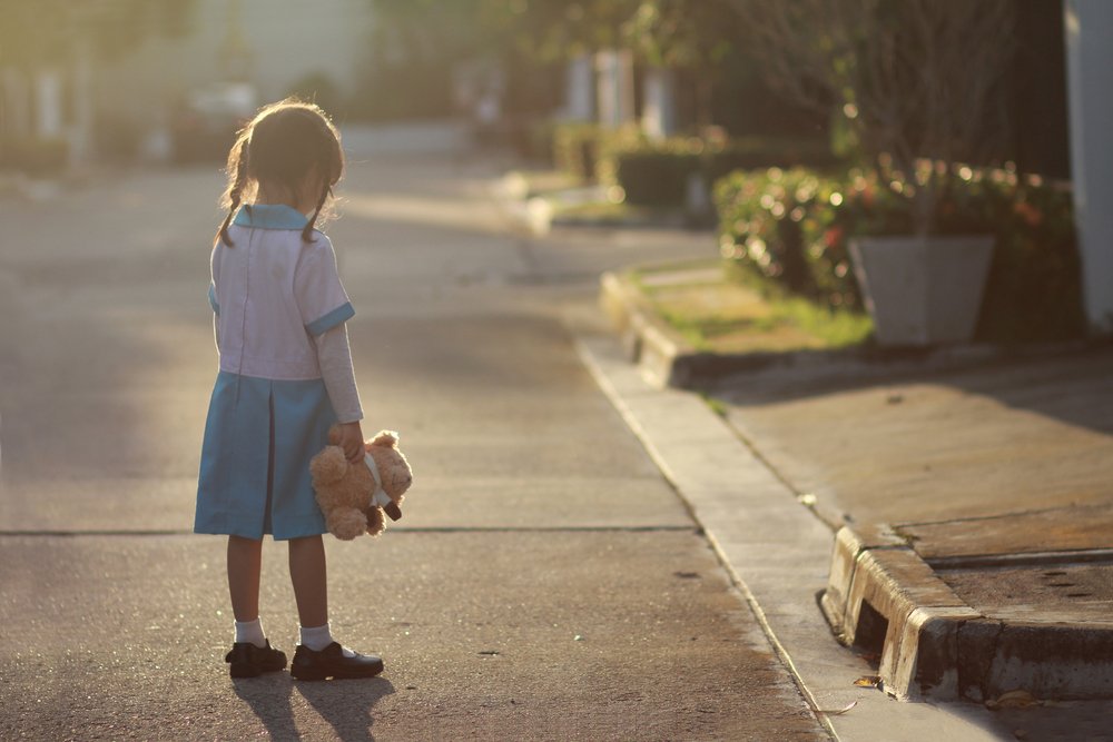 Niña afligida en medio de la calle sosteniendo un peluche. | Foto: Shutterstock