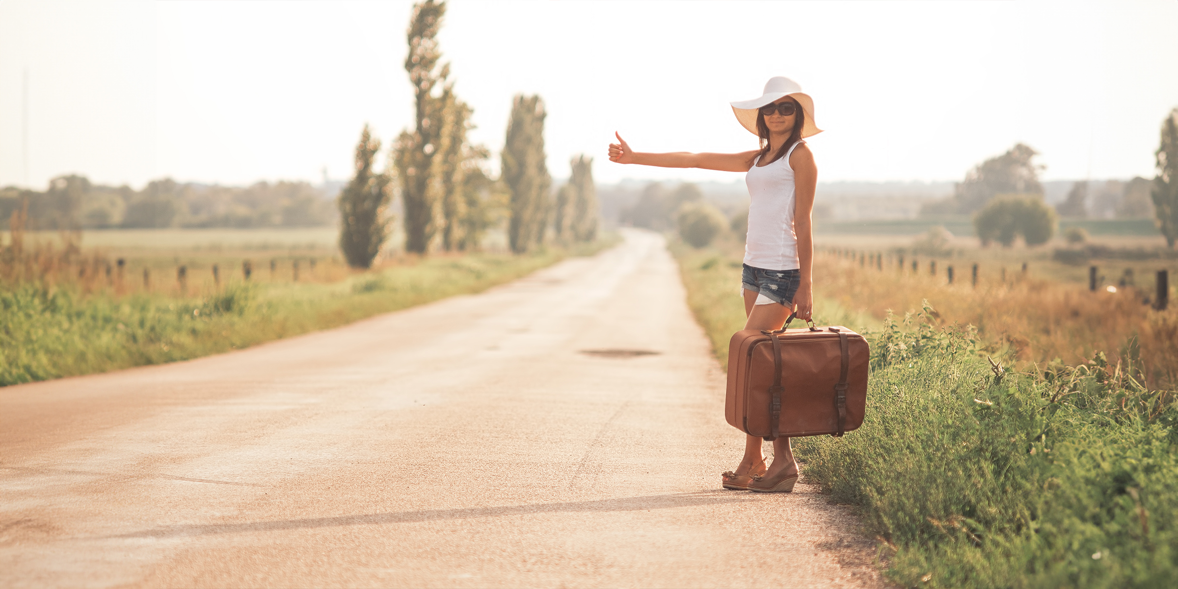 Young woman with a suitcase on a road | Source: Shutterstock