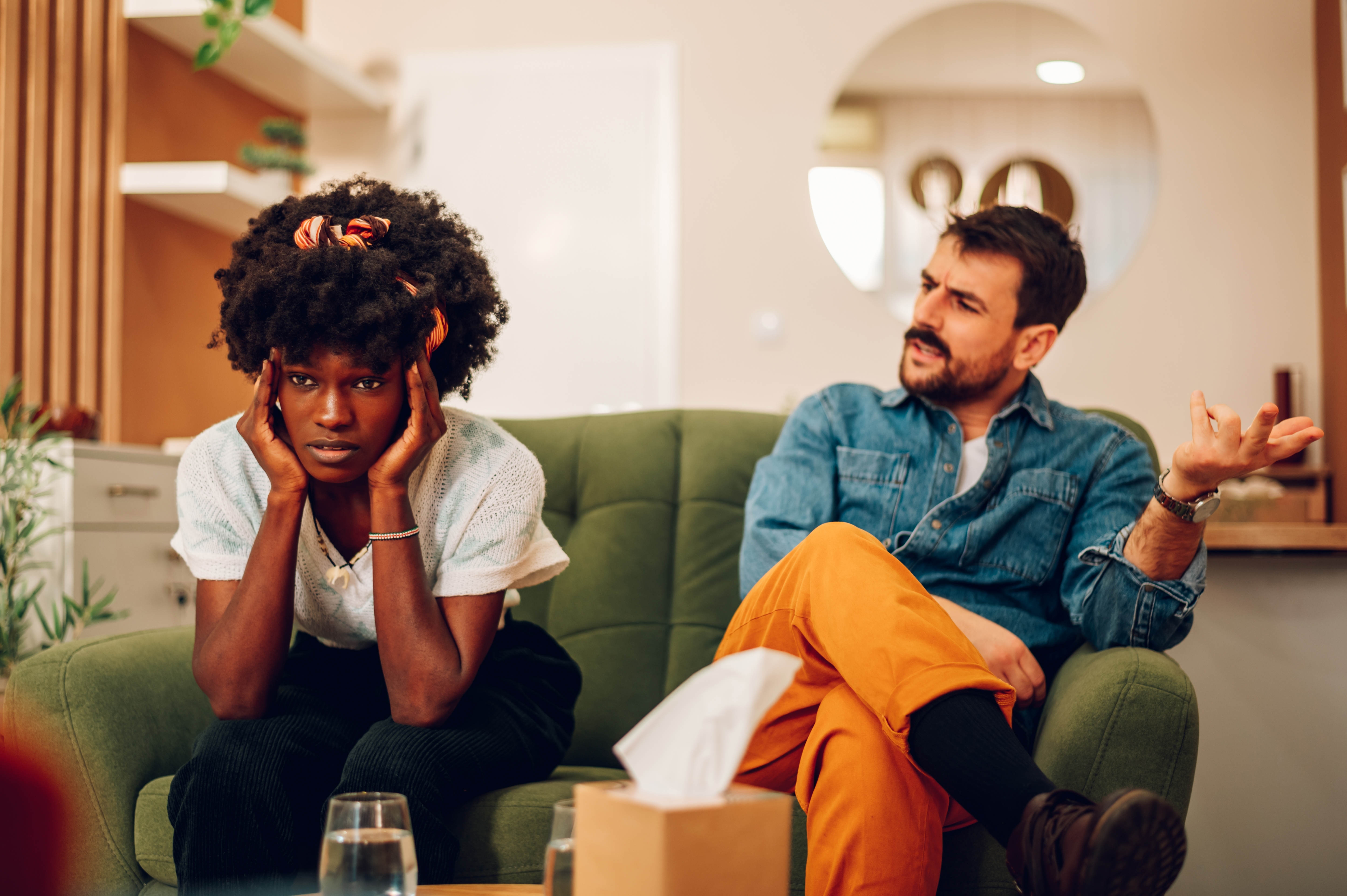 Ein weißer Mann und eine schwarze Frau haben eine Meinungsverschiedenheit, während sie auf einer Couch sitzen. | Quelle: Shutterstock