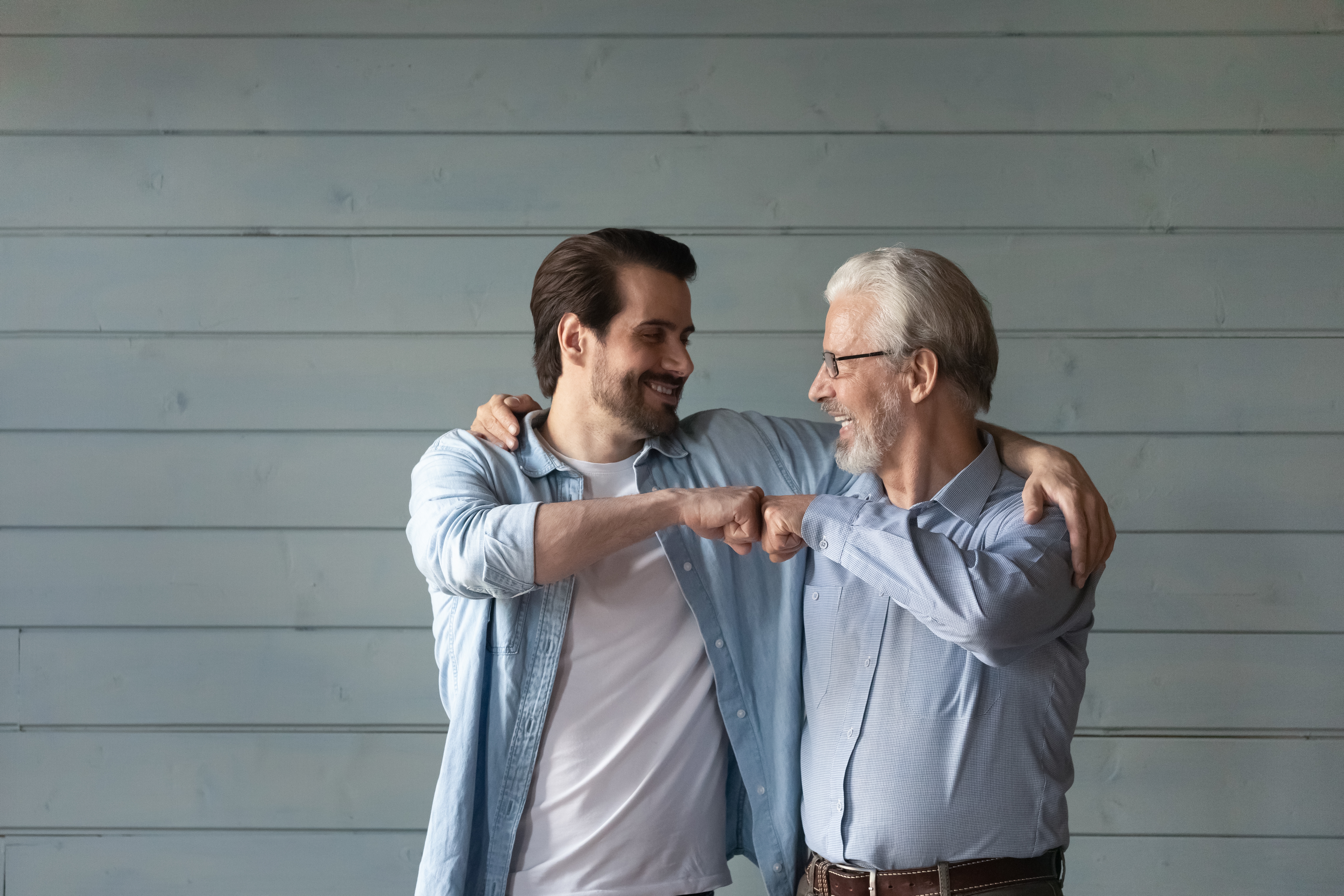 An older man bumping his fist with a younger man | Source: Shutterstock