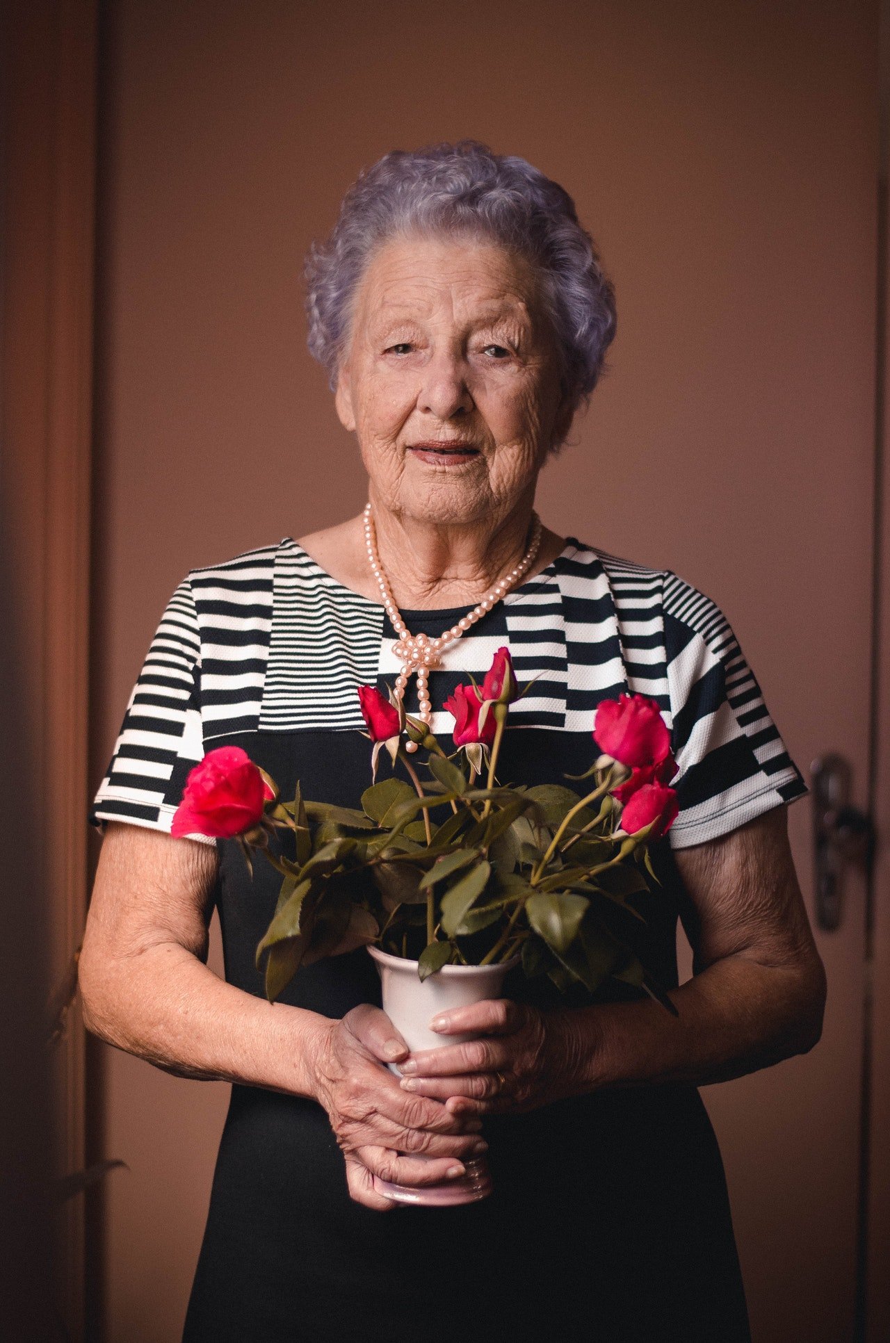 Anciana con flores en las manos. | Foto: Pexels