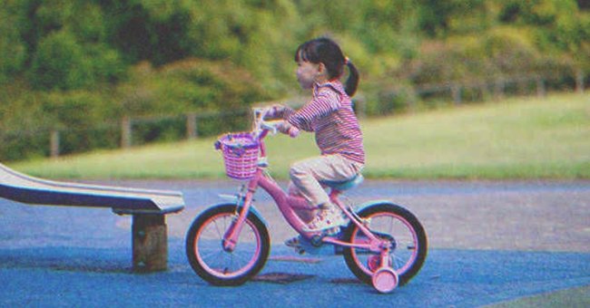 Niña manejando una bicicleta cerca de un tobogán. | Foto: Shutterstock