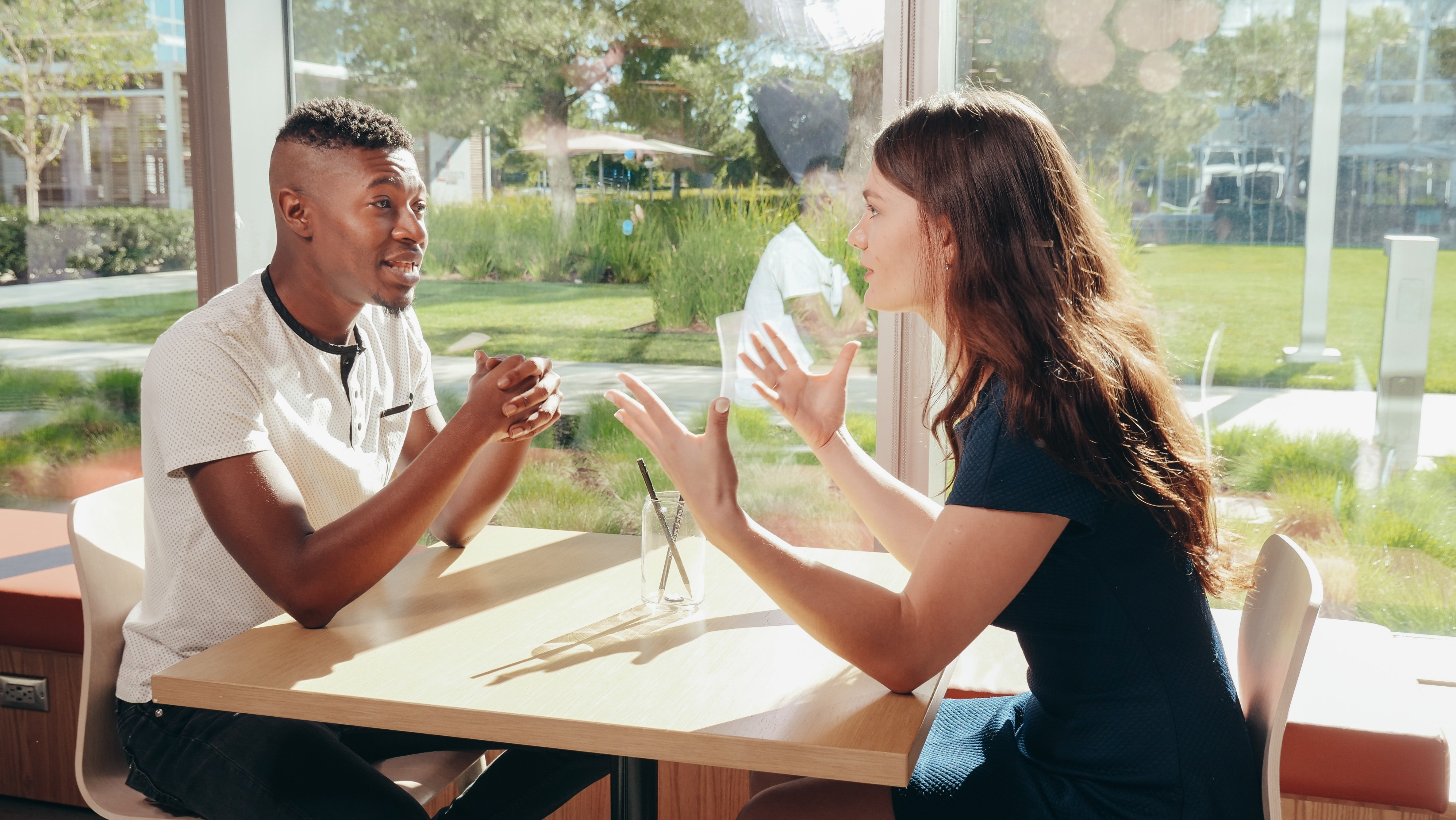 A young woman and man having a conversation whilst seated by a window | Source: Pexels/ Kindel Media