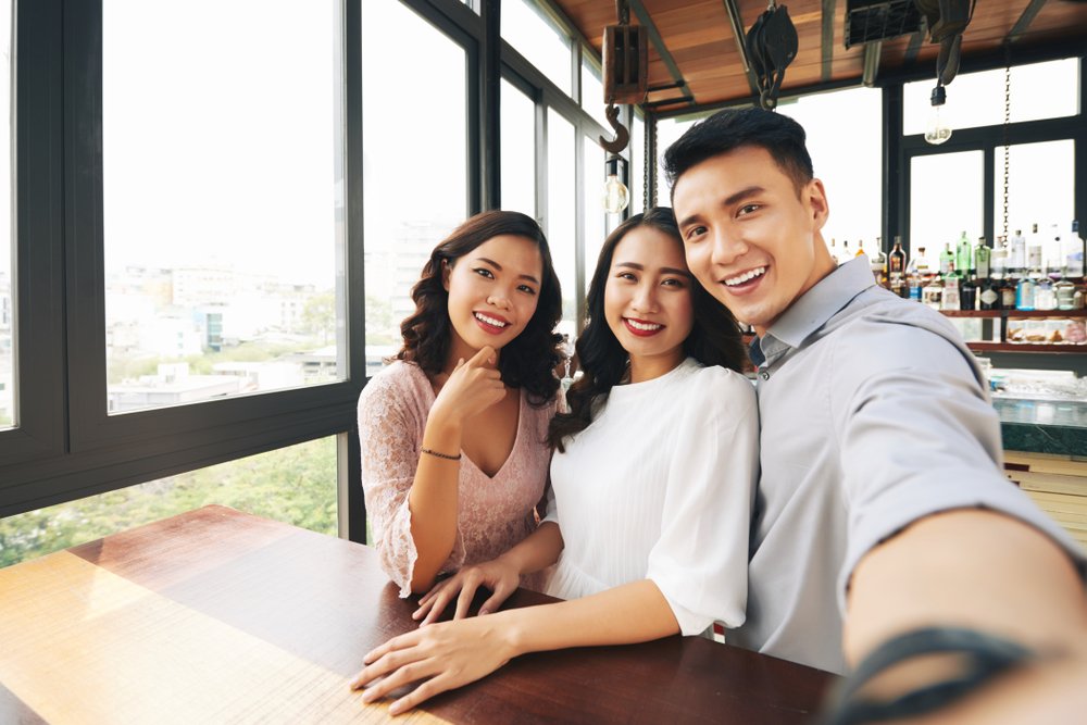 Three siblings taking a photo at a bar. | Photo: Shutterstock