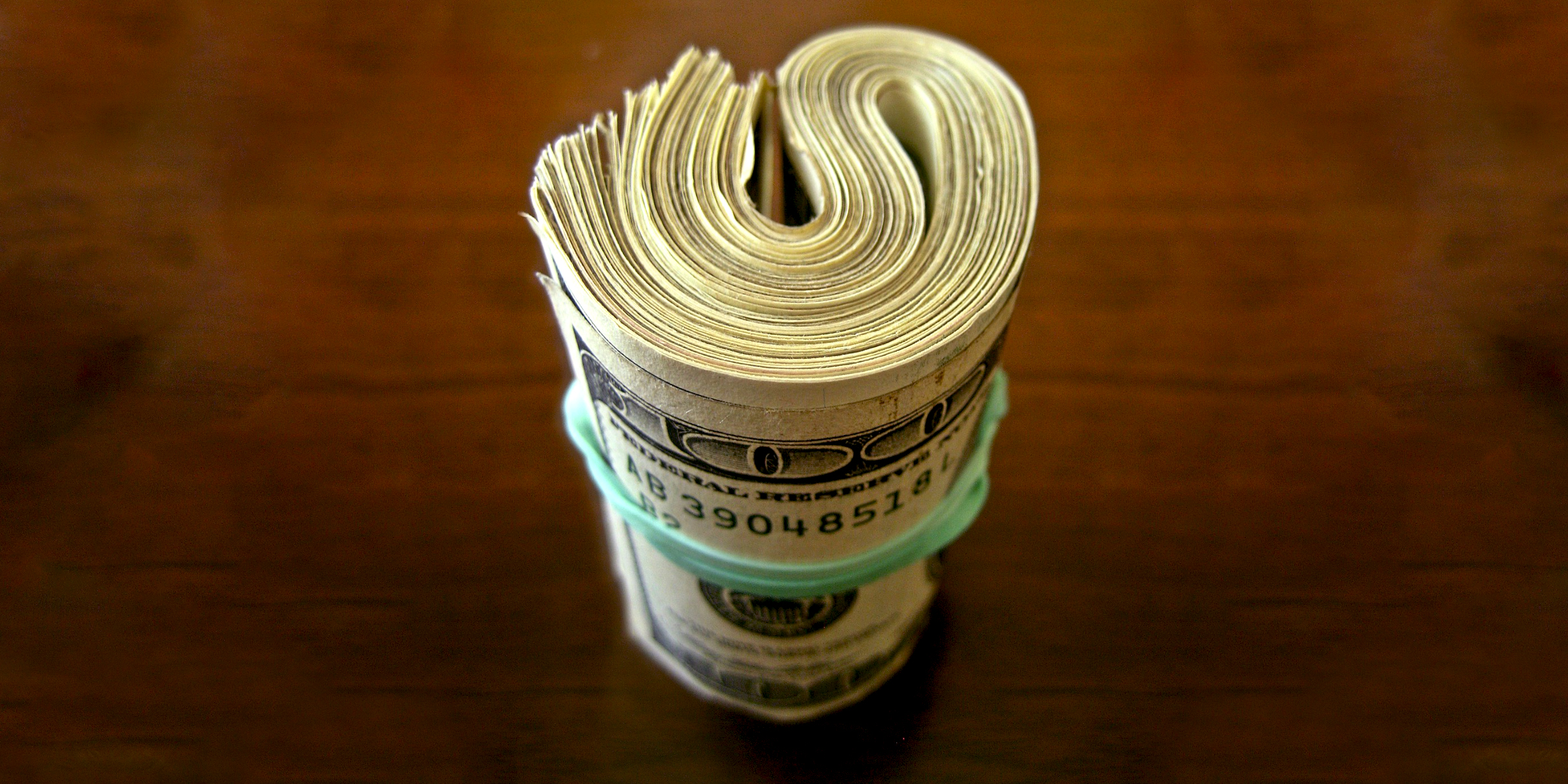 A wad of dollar bills bound with a rubber band | Source: Flickr