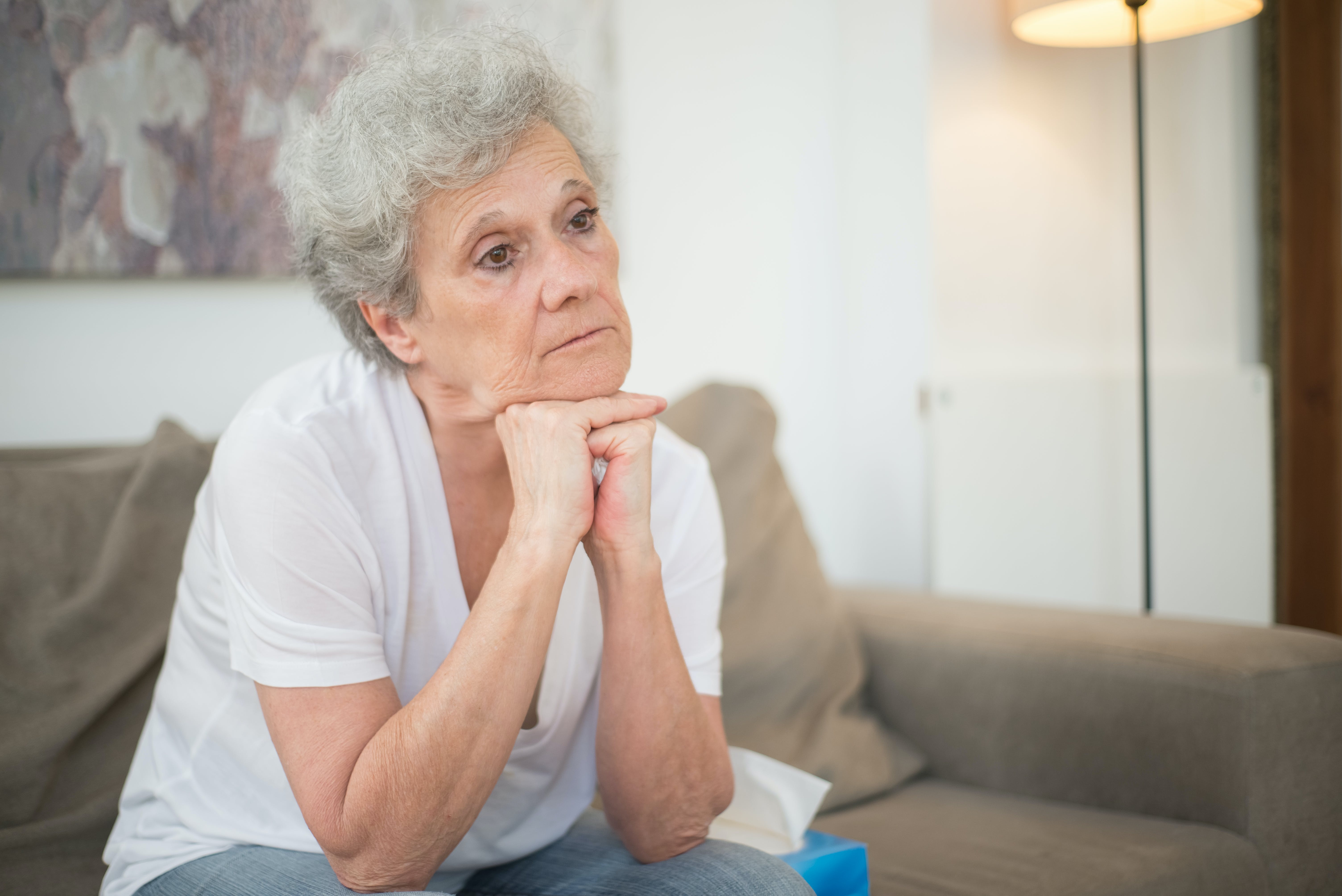 An upset older woman sitting with her hands under her chin | Source: Pexels