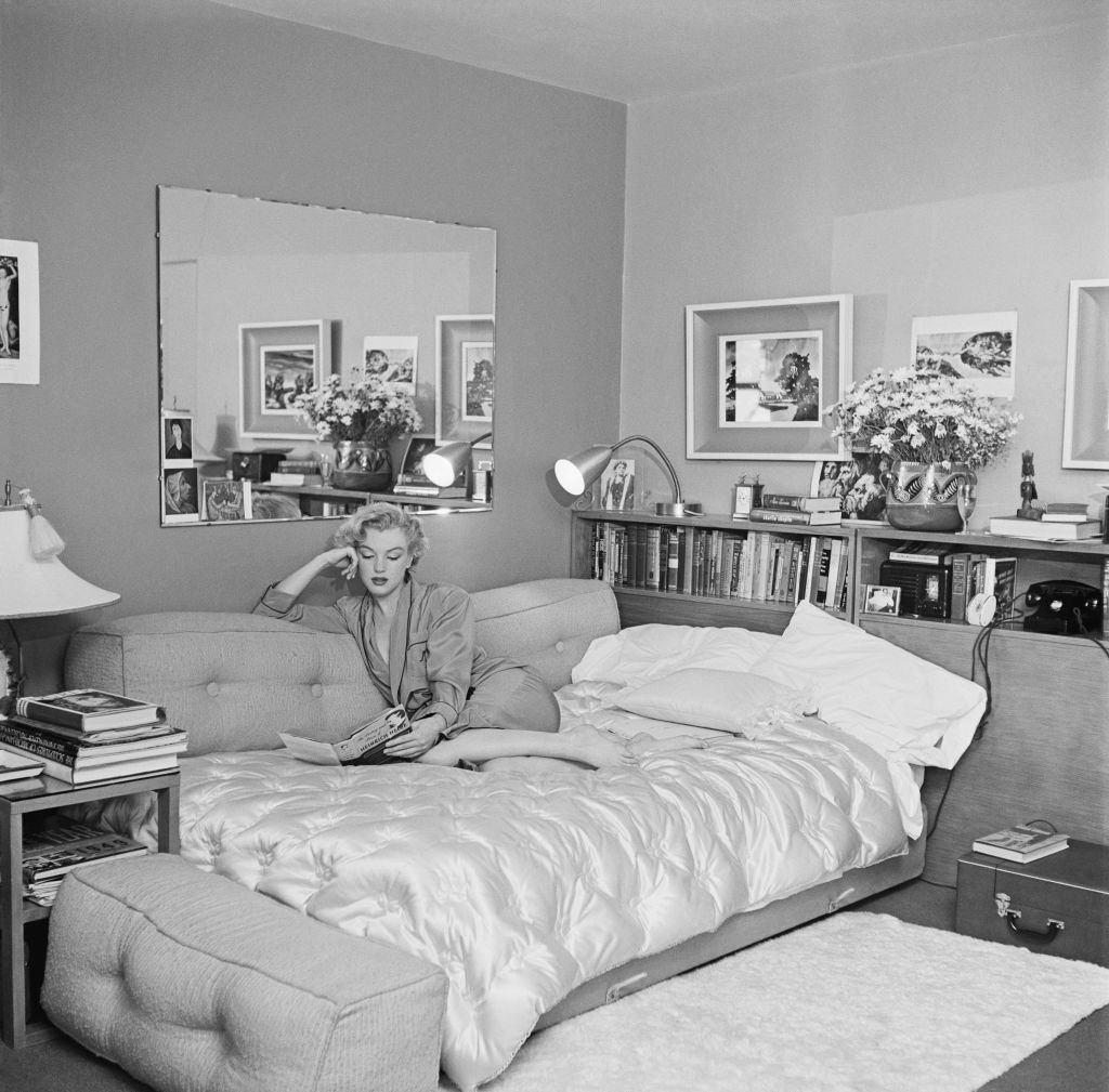 Marilyn Monroe sobre un sofá cama leyendo "La poesía y la prosa de Heinrich Heine", alrededor de 1951. | Foto: Getty Images
