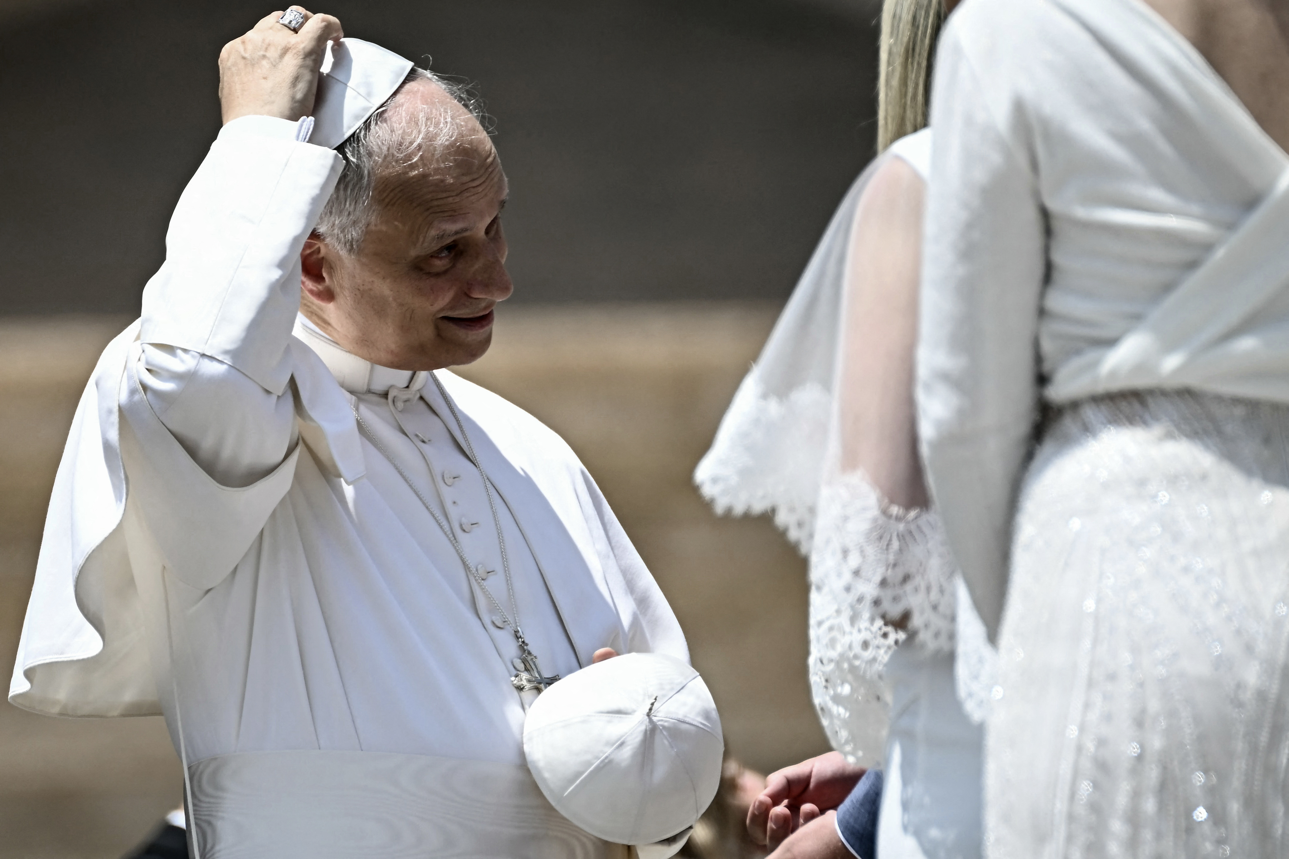 Pope Leo XIV smiles as he lifts his skullcap while meeting a bride during the traditional greeting with newlywed couples in St. Peter's Square on June 11, 2025 | Source: Getty Images
