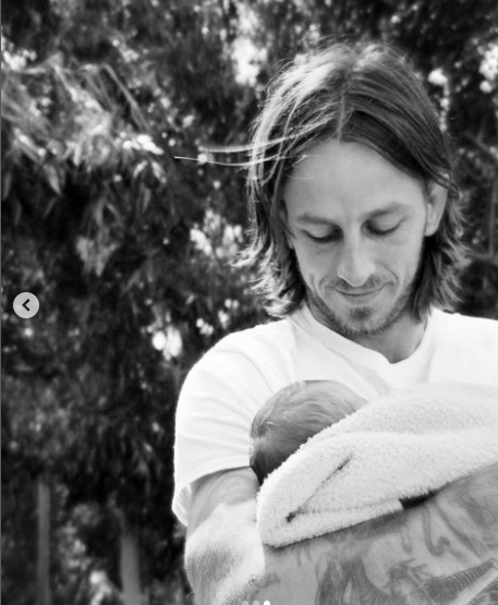 Riley Hawk pictured holding his newborn son, dated September 29, 2024 | Source: Instagram/thespaceswitch