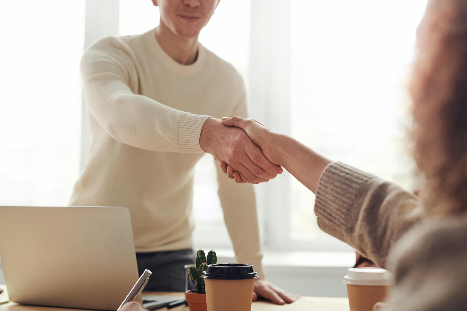 A man and woman shaking hands in an office setting | Source: Pexels