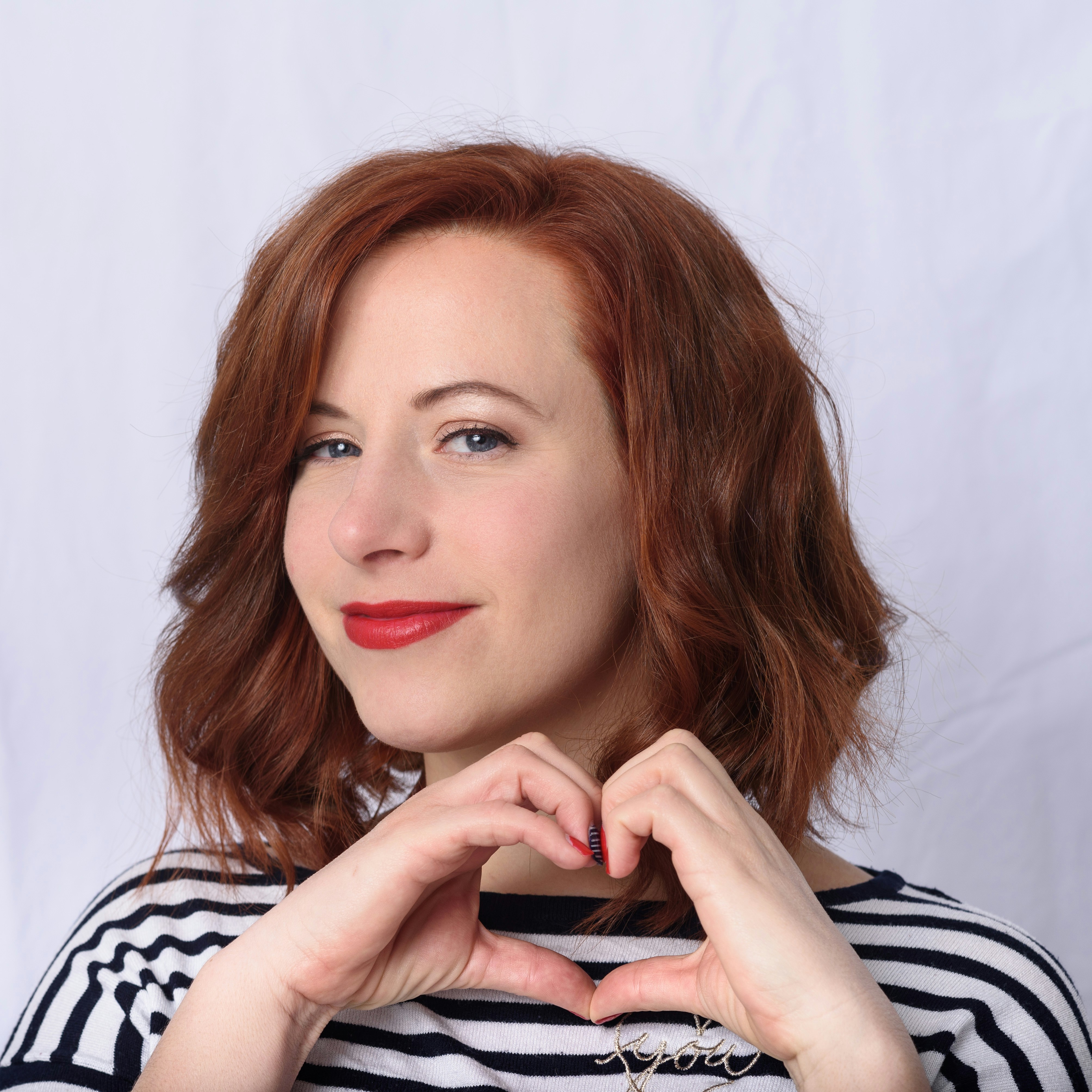 A smiling woman signing a heart with her hands | Source: Unsplash