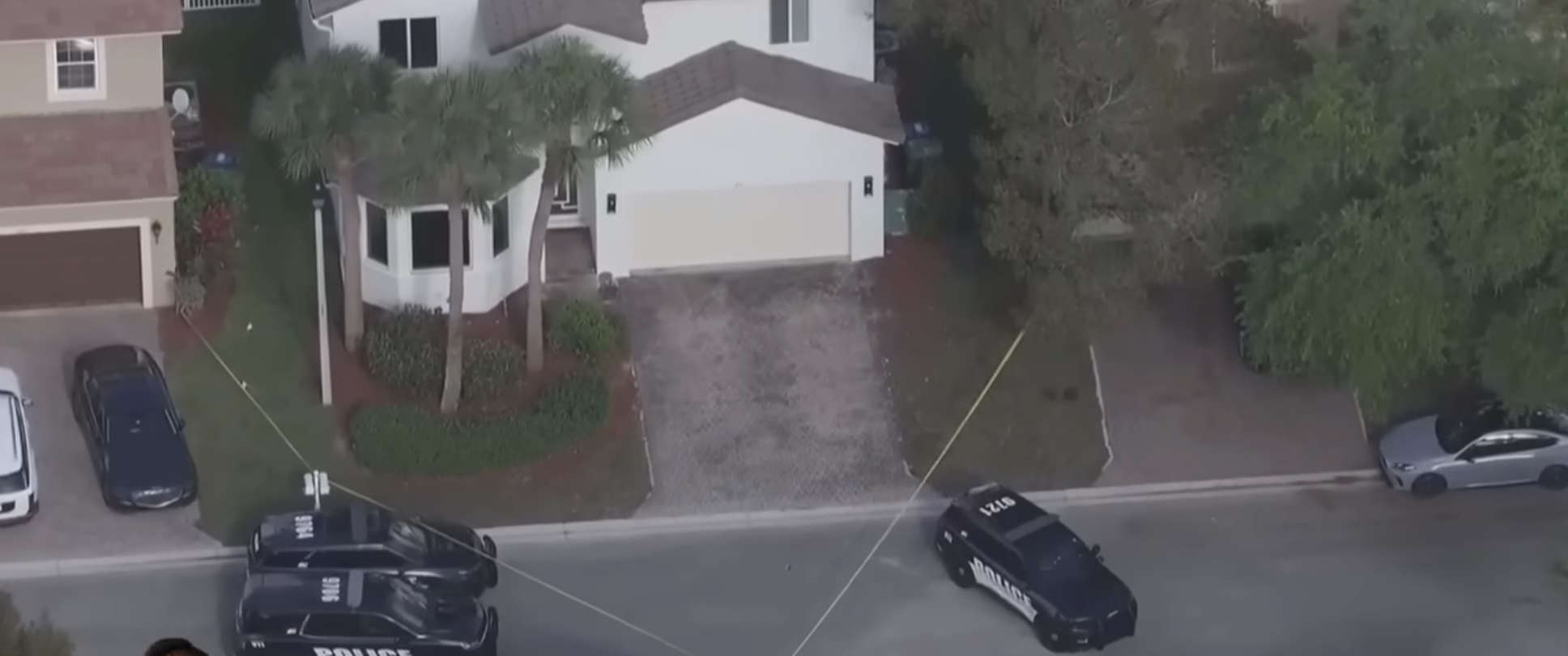 A closer overhead shot focuses on the couple's residence at the center of the investigation, with police tape stretched across the street and several marked vehicles positioned around the property. | Source: YouTube/WPLG Local 10