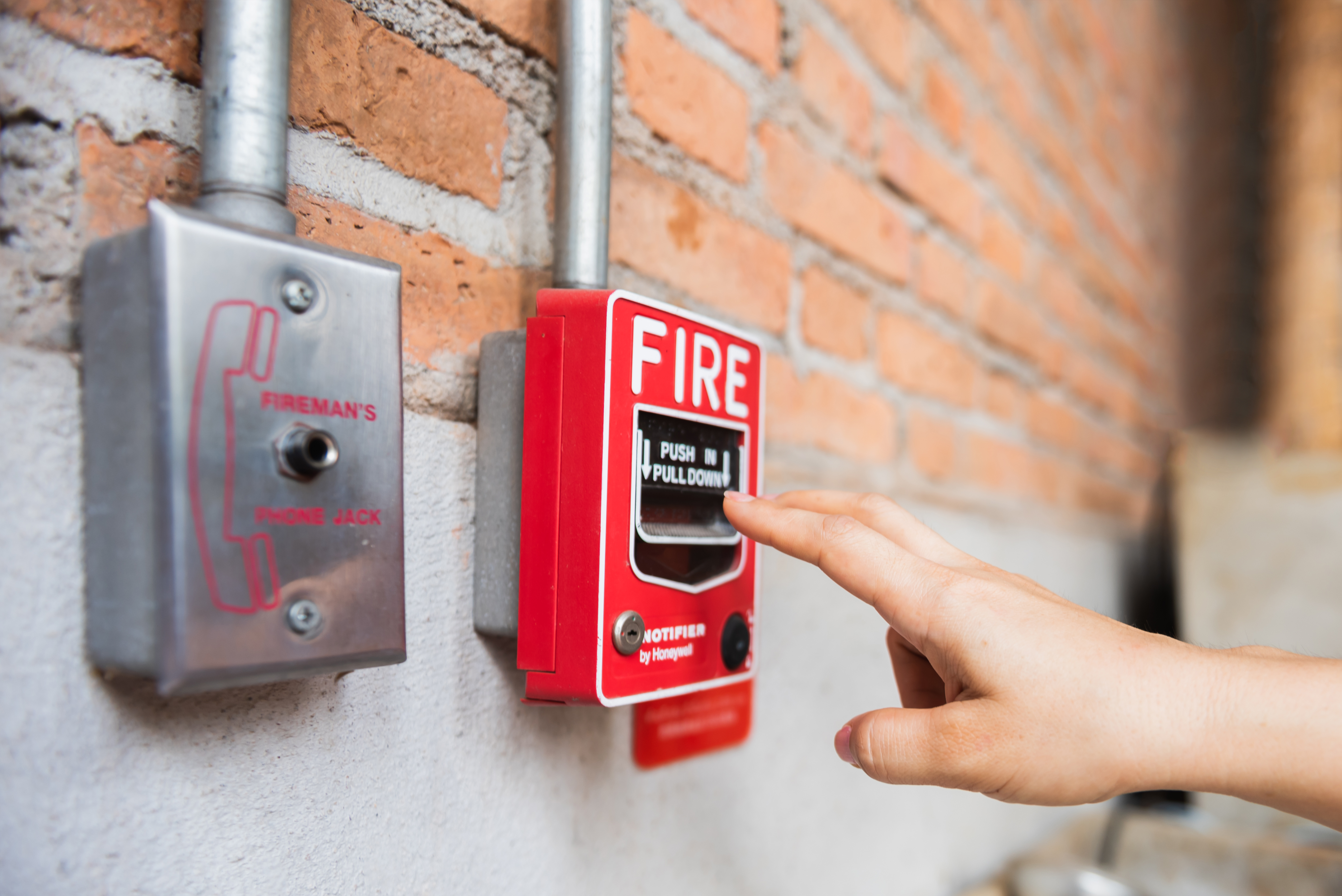 Hand of woman reaching to Fire alarm switch system | Source: Getty Images