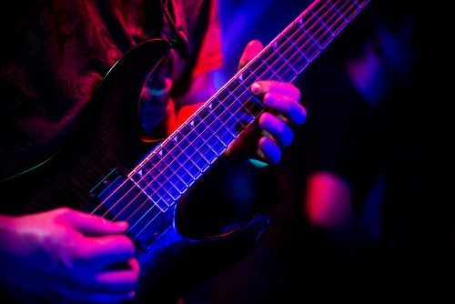 Guitarist playing with dimmed lighting. | Source: Shutterstock.