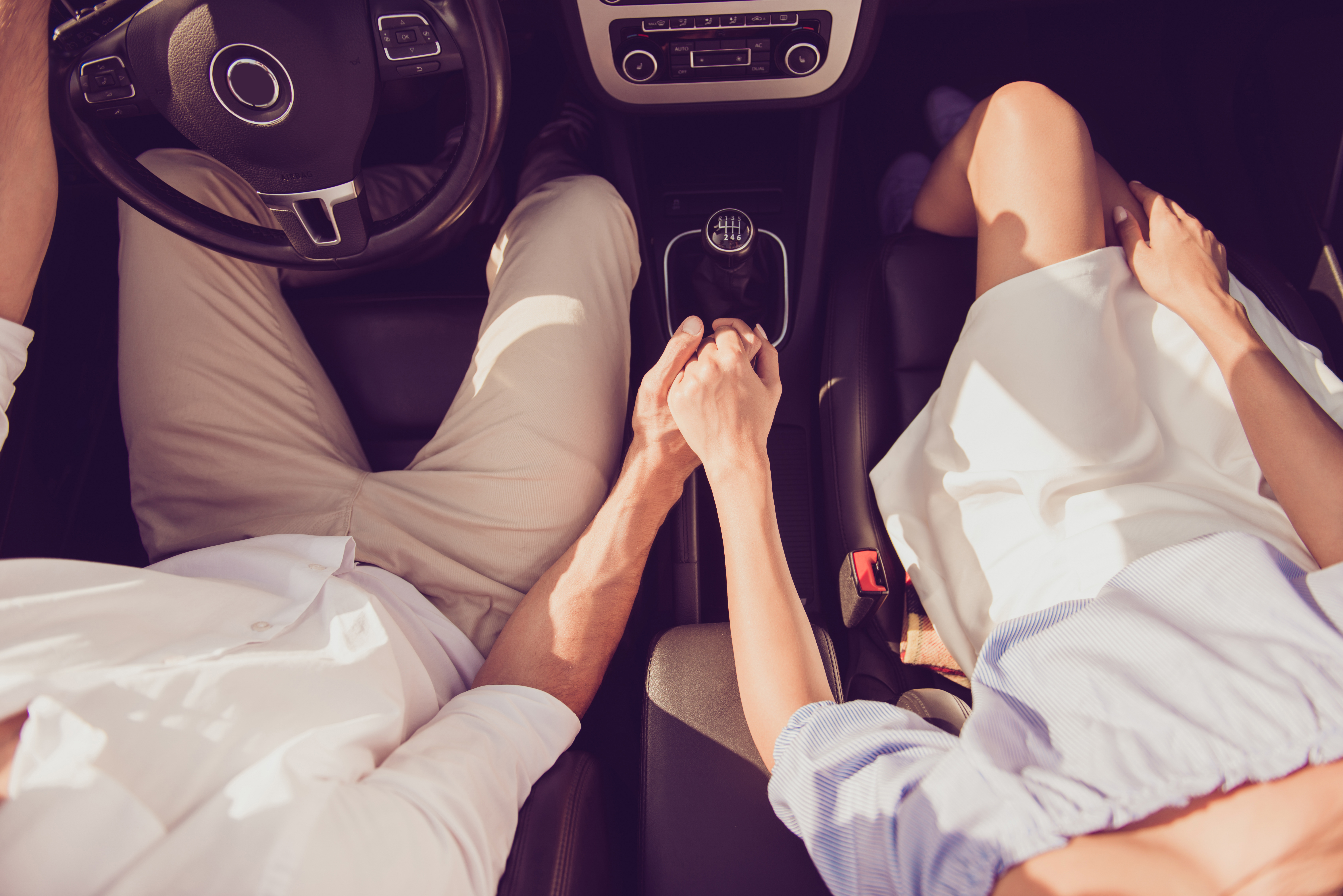 A couple holding hands in a car | Source: Shutterstock