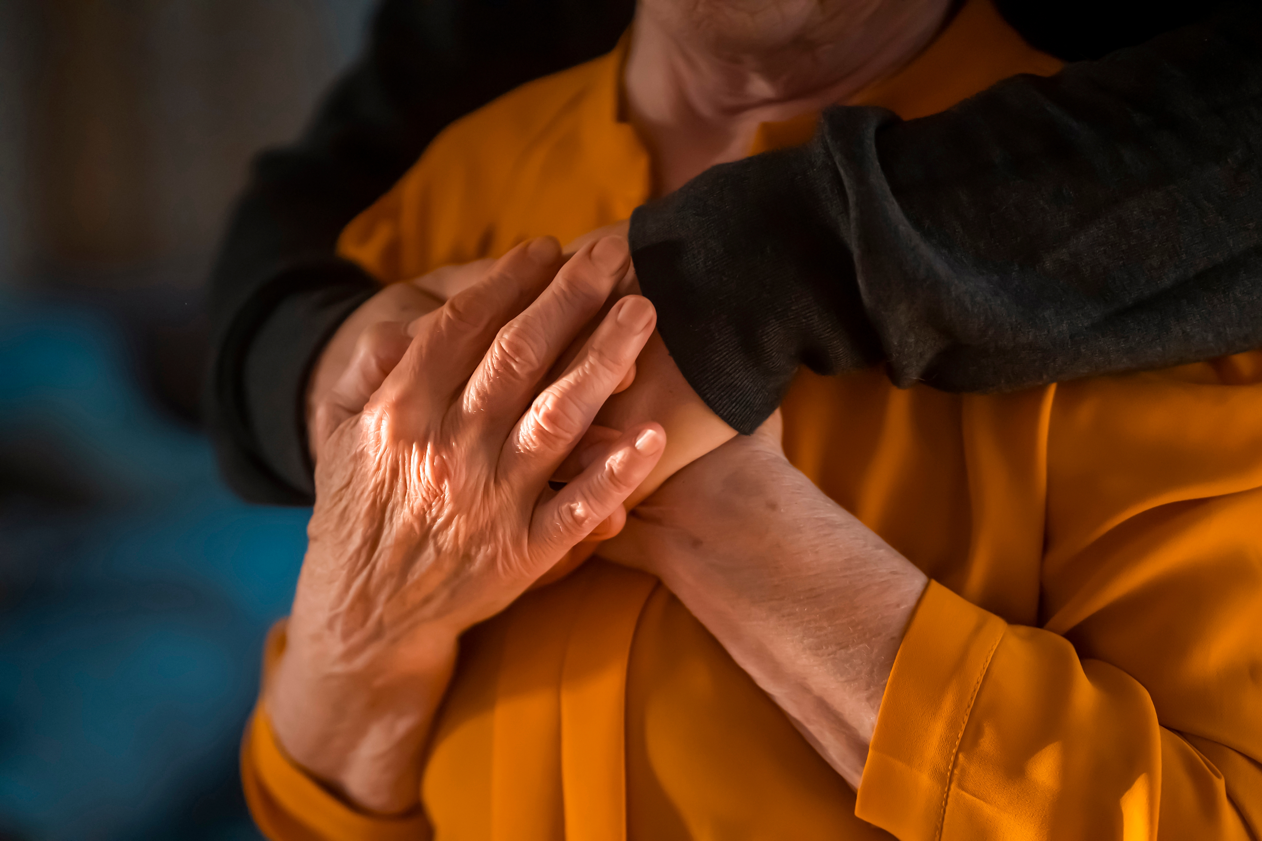 A senior mom holding her son's hands as a gesture of comfort and support | Source: Shutterstock