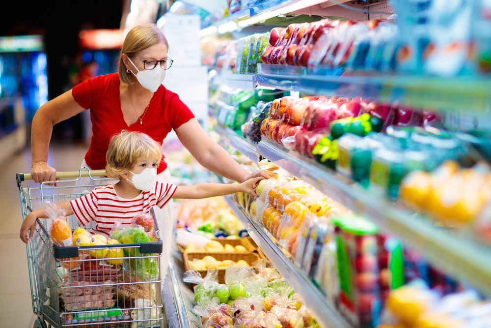 A mother and child wearing surgical face masks while shopping at a supermarket | Photo: Shutterstock/FamVeld