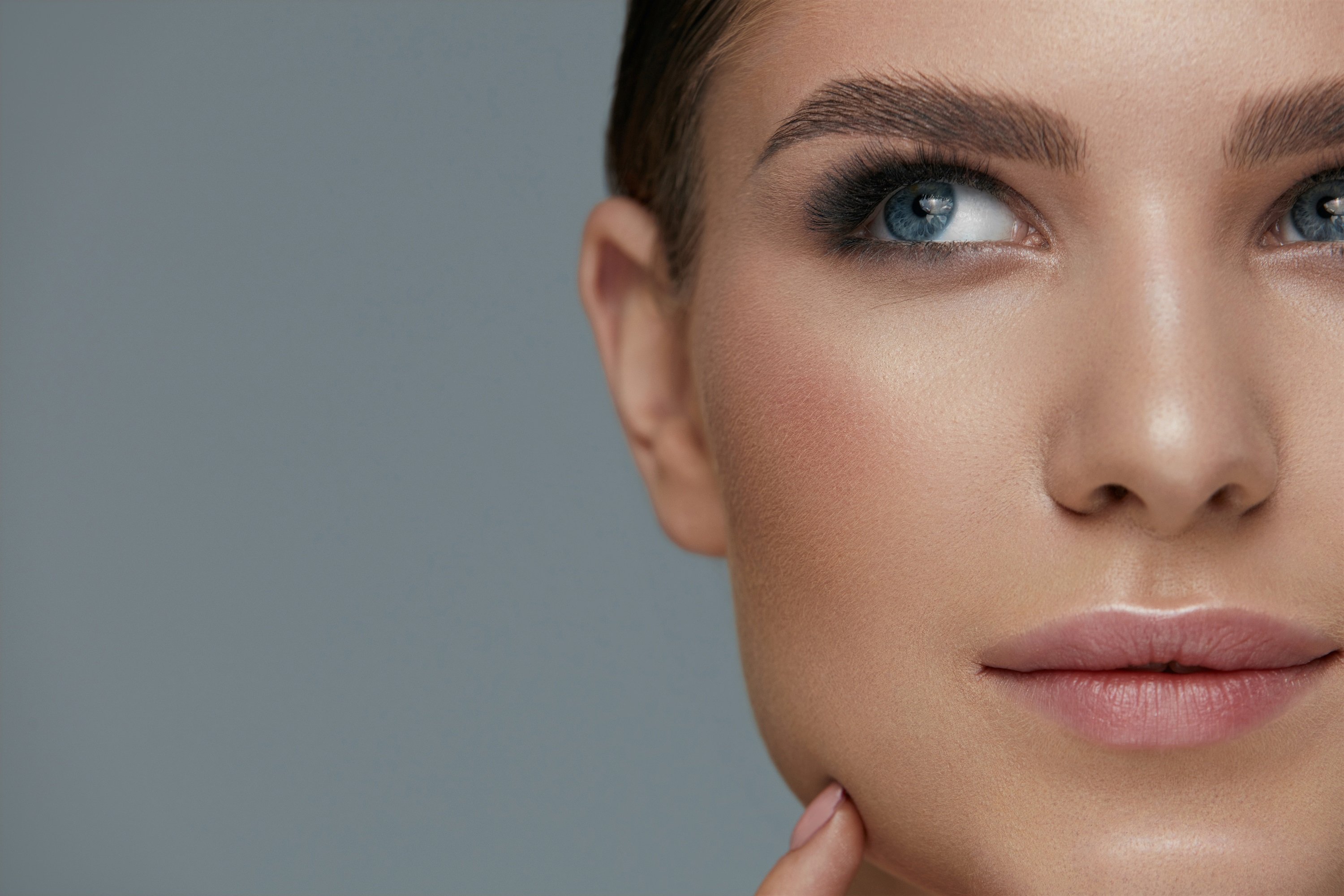Mujer con cejas impecables mira hacia arriba. | Foto: Shutterstock