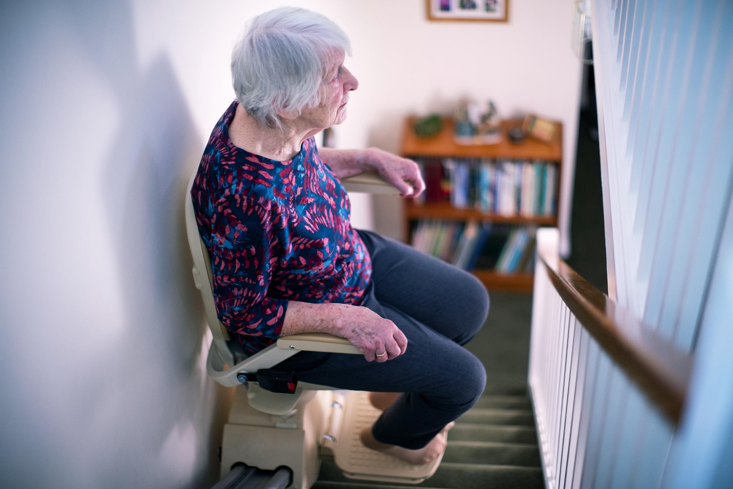 Senior woman sitting on a stair lift at home | Source: Shutterstock