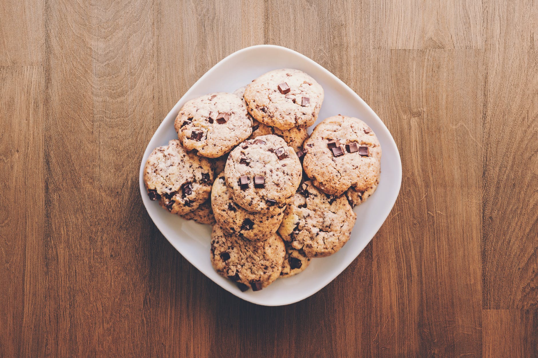Freshly baked chocolate chip cookies on a white ceramic plate. | Photo: Pexels.