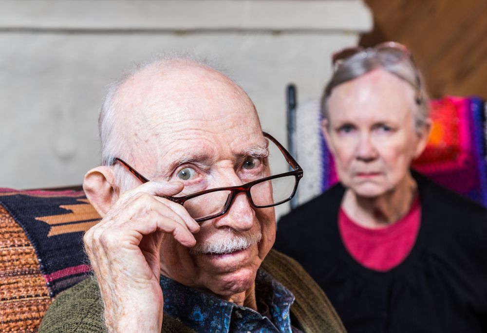 An old man looking at the camera with a woman behind him. | Source: Shutterstock