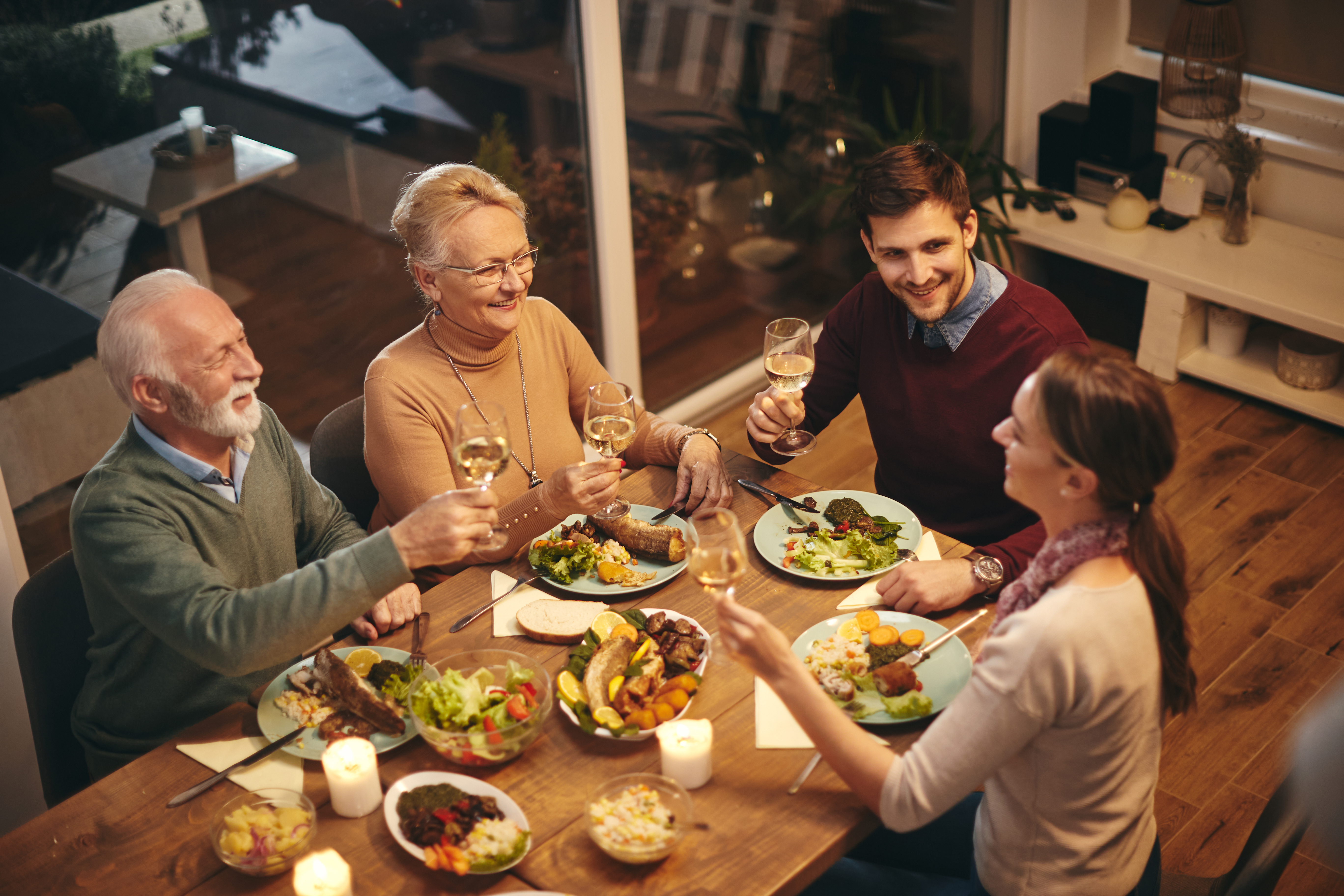 High angle view of happy senior woman toasting with her family while having a meal at dining table. | Source: Shutterstock