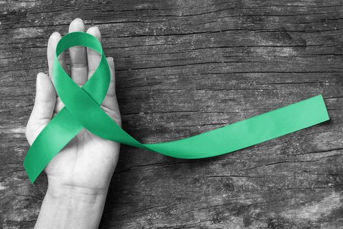 Persona sostiene en su mano una cinta verde, símbolo de la concientización de la donación de órganos. | Foto: Shutterstock