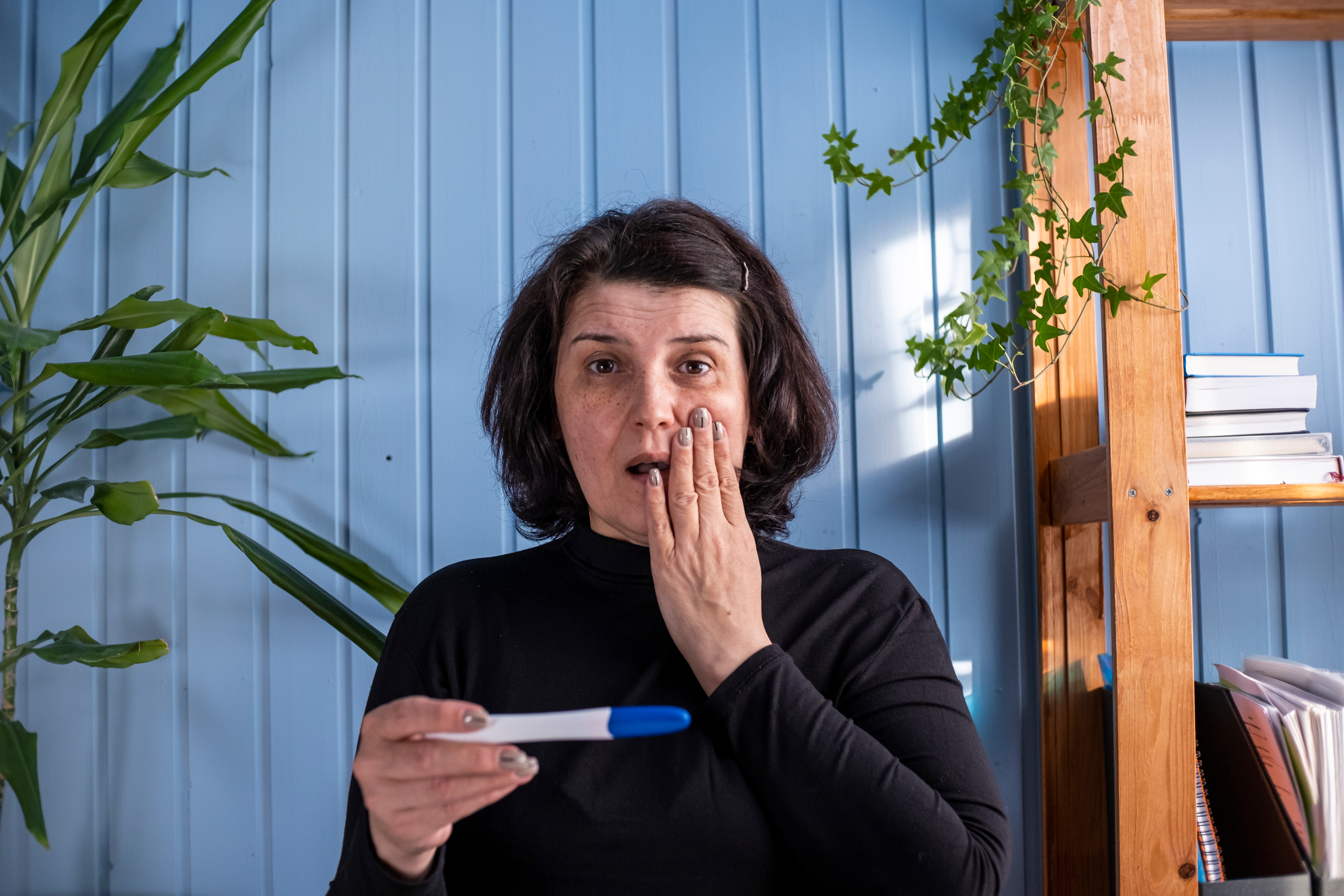 A middle-aged woman looking at a pregnancy test result showing positive | Source: Shutterstock