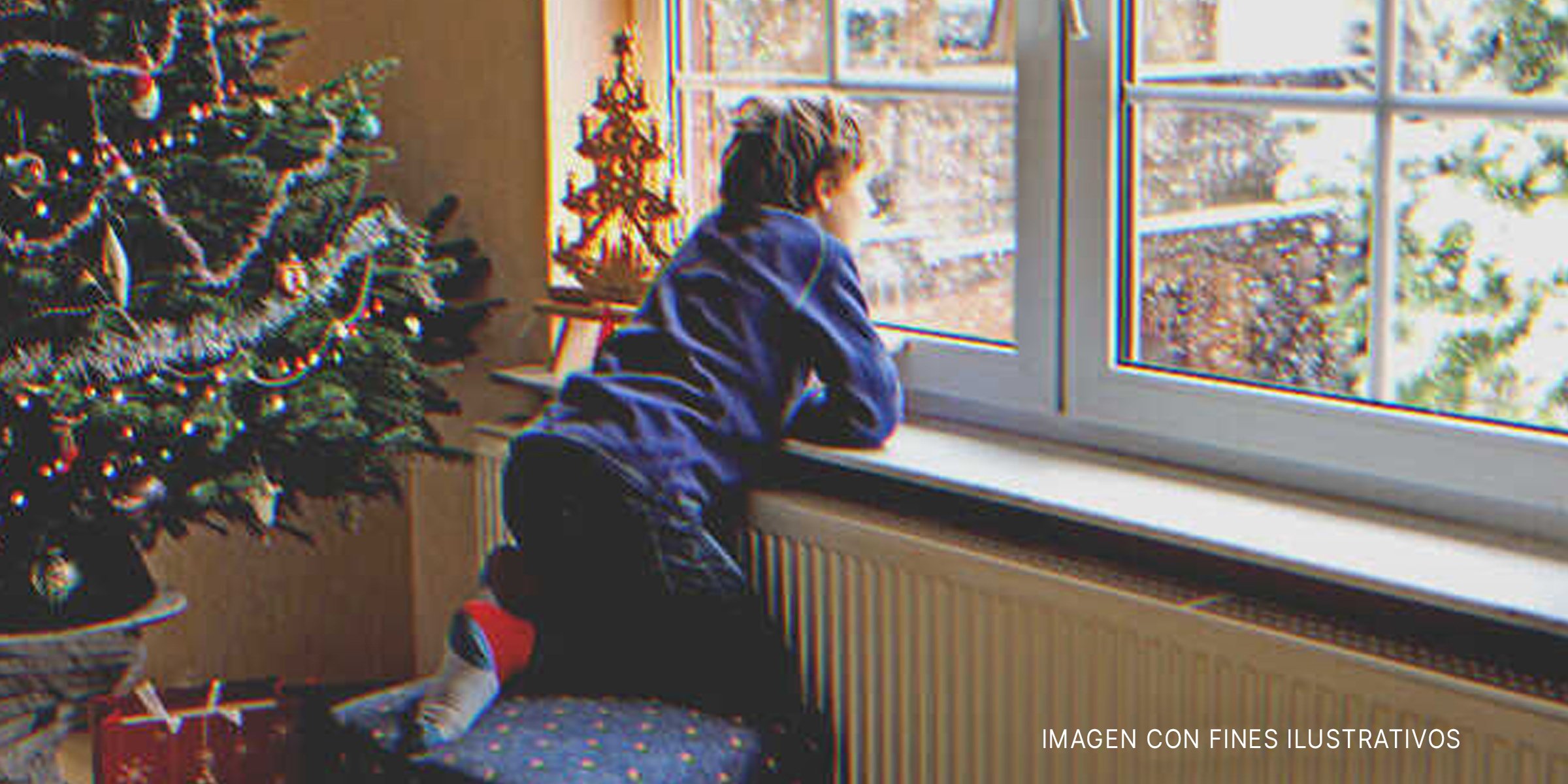 Un niño mirando por la ventana durante la Navidad.| Foto: Shutterstock