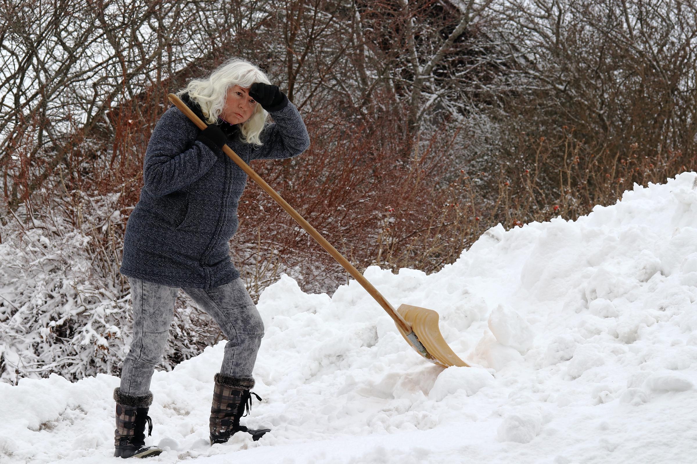 Woman appearing stressed while shoveling snow | Source: Shutterstock