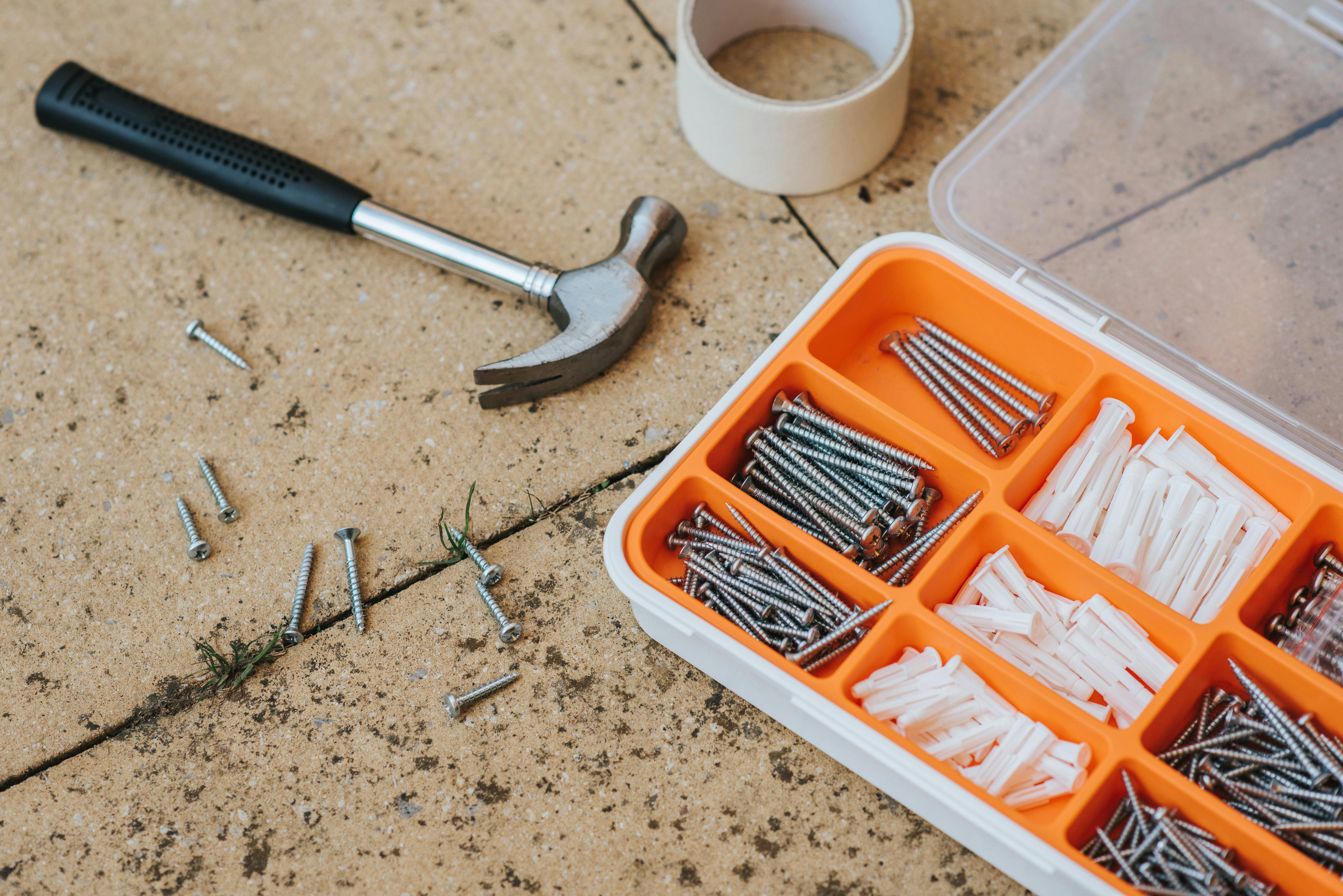 Screws and repair tools in a box near a hammer | Source: Pexels