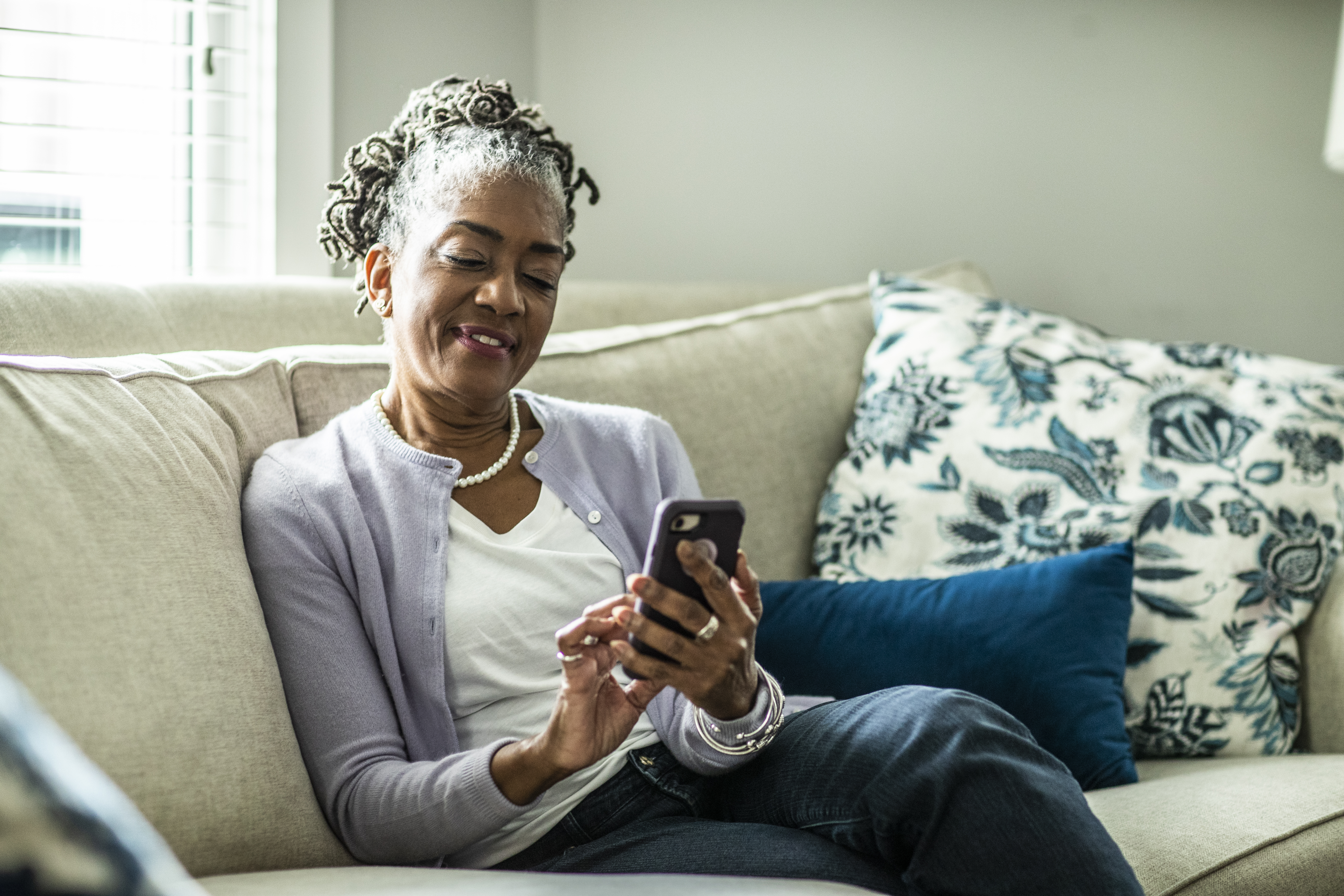 Senior woman using smartphone in living room of suburban home | Source: Getty Images
