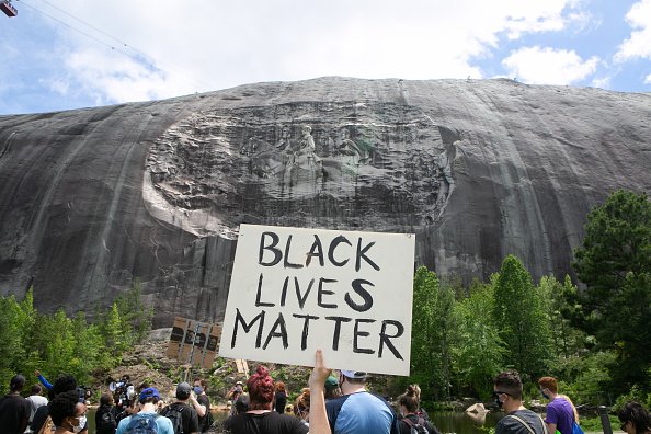 A protester holds a Black Lives Matter sign in front of the Confederate carving in Stone Mountain Park on June 16, 2020 in Stone Mountain, Georgia. | Photo: Getty Images