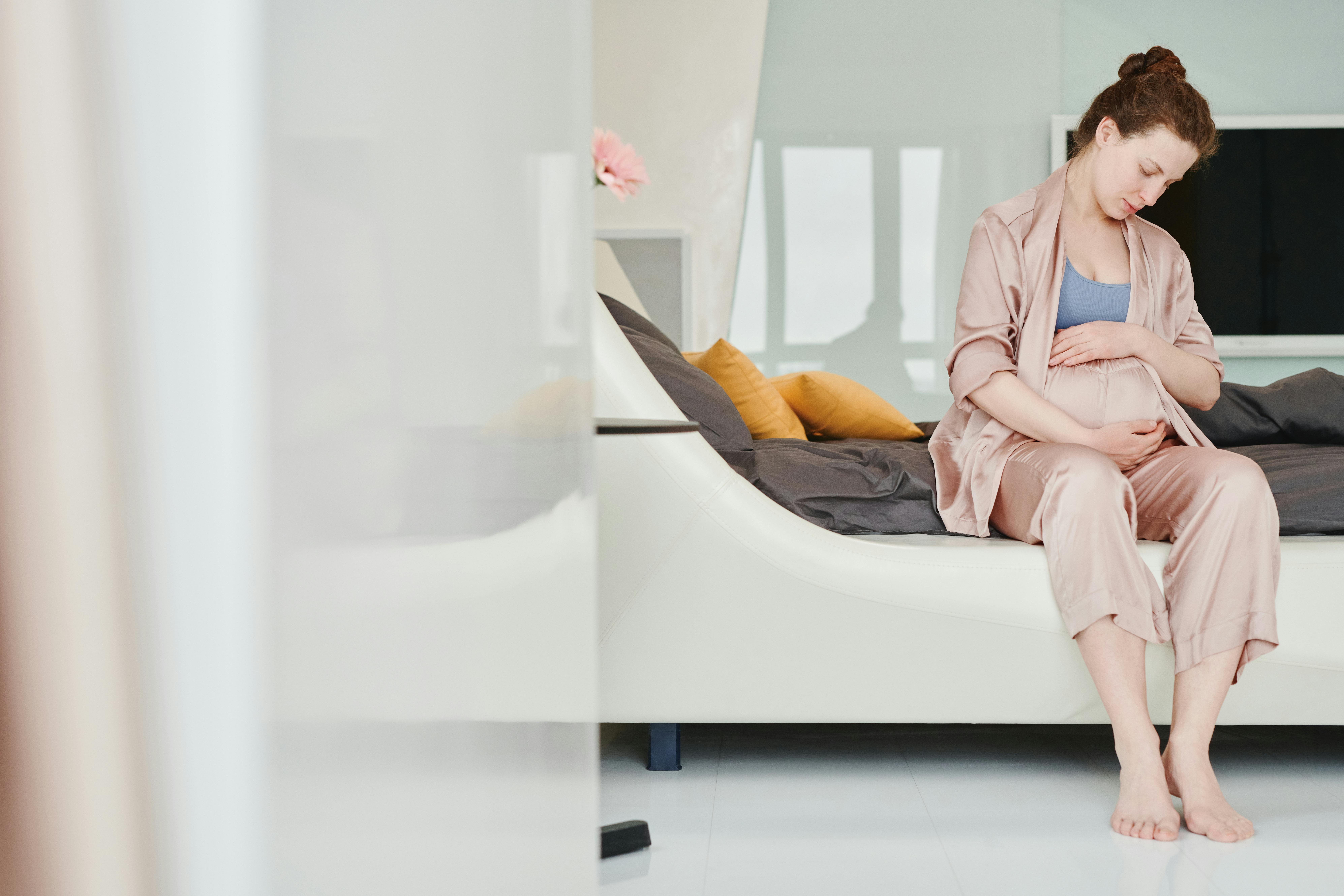 A woman sitting and cradling her pregnant belly | Source: Pexels