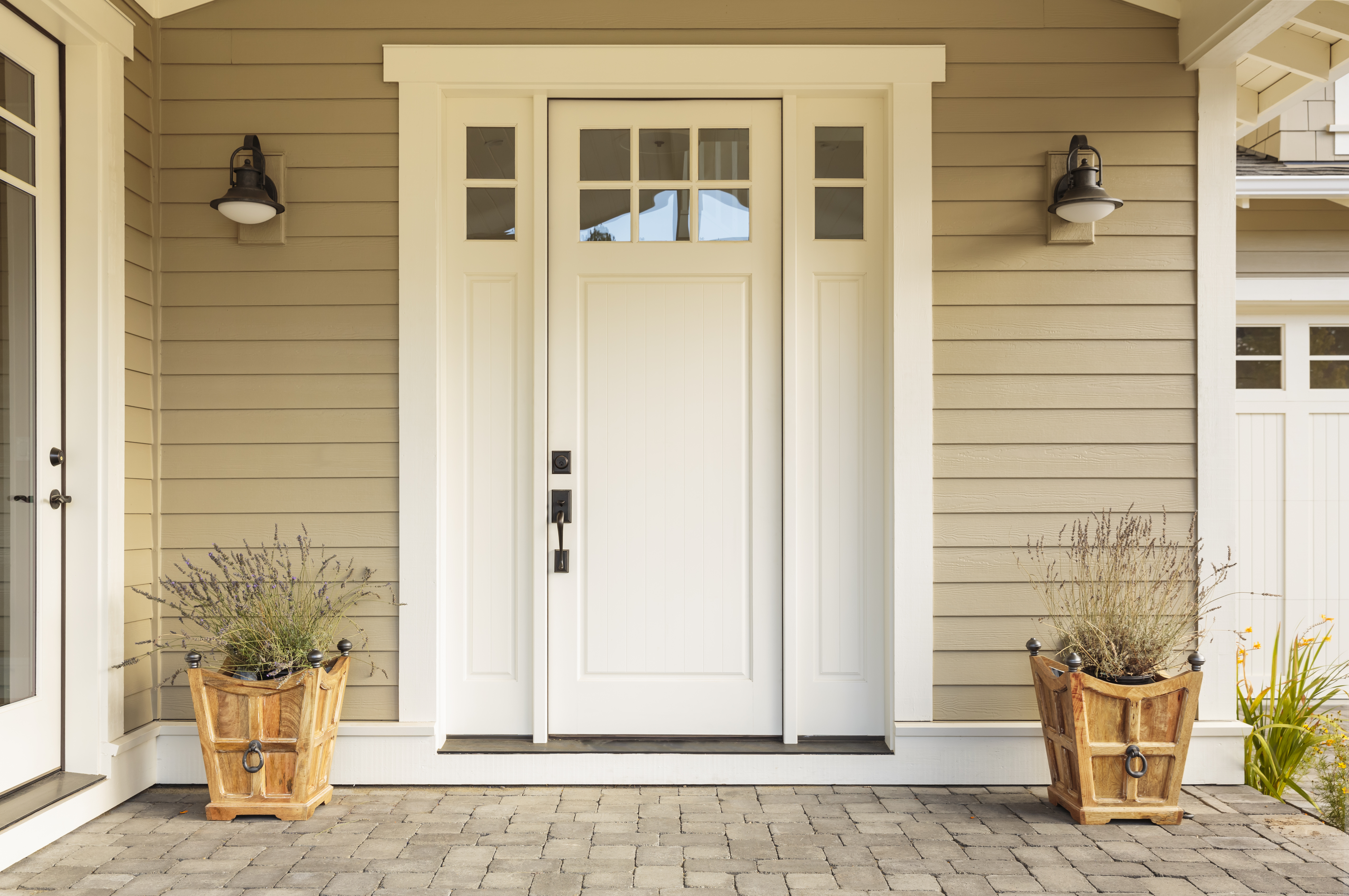 Puerta de entrada blanca con pequeñas ventanas decorativas cuadradas y macetas |  Fuente: Shutterstock