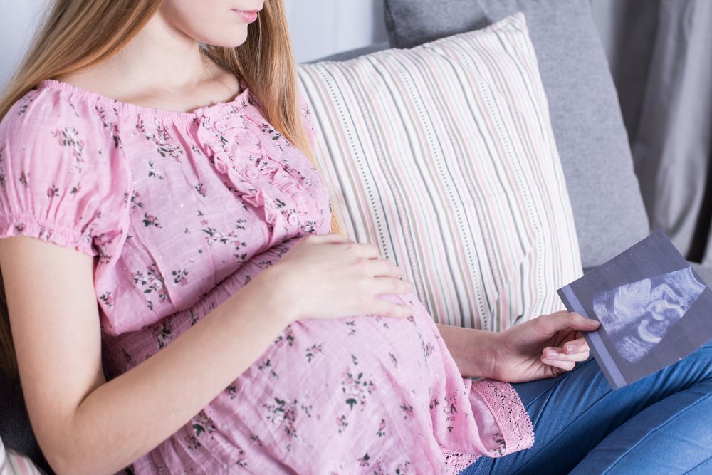 Cropped picture of a young woman looking at a USG picture of her baby | Photo: Shutterstock