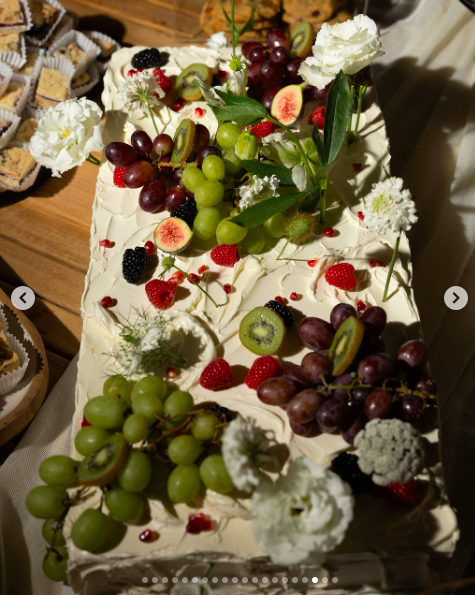 The flat, rectangular, floral-topped cake adorned with fresh fruit by Just Baked, and other pastries. | Source: Instagram/samkoma.world and maksmaakphoto