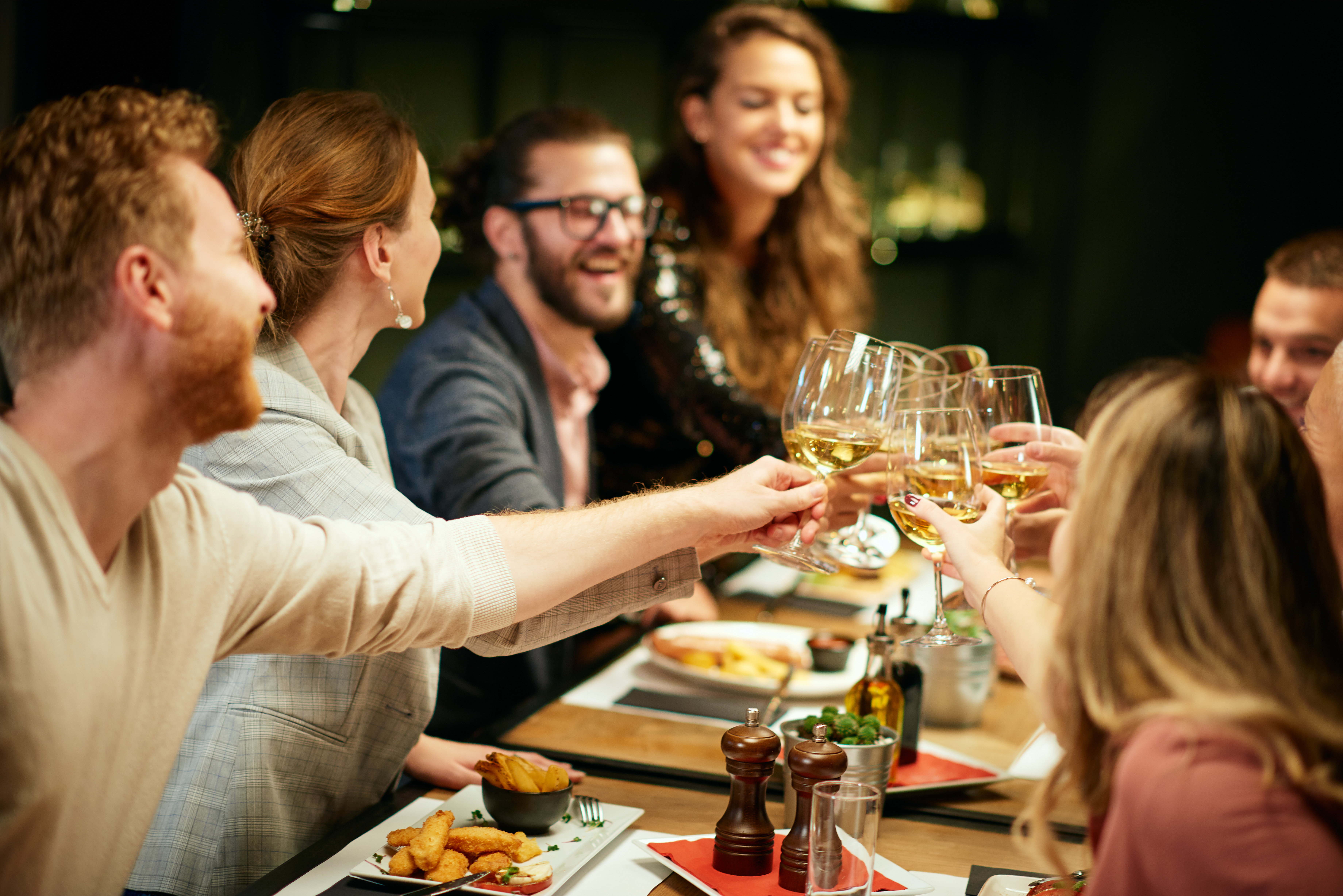 A group of friends sitting in a restaurant for dinner and raising their glasses | Source: Shutterstock