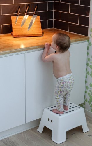 A small child is curious and looks at big sharp knives on a kitchen counter. | Source: Shutterstock.