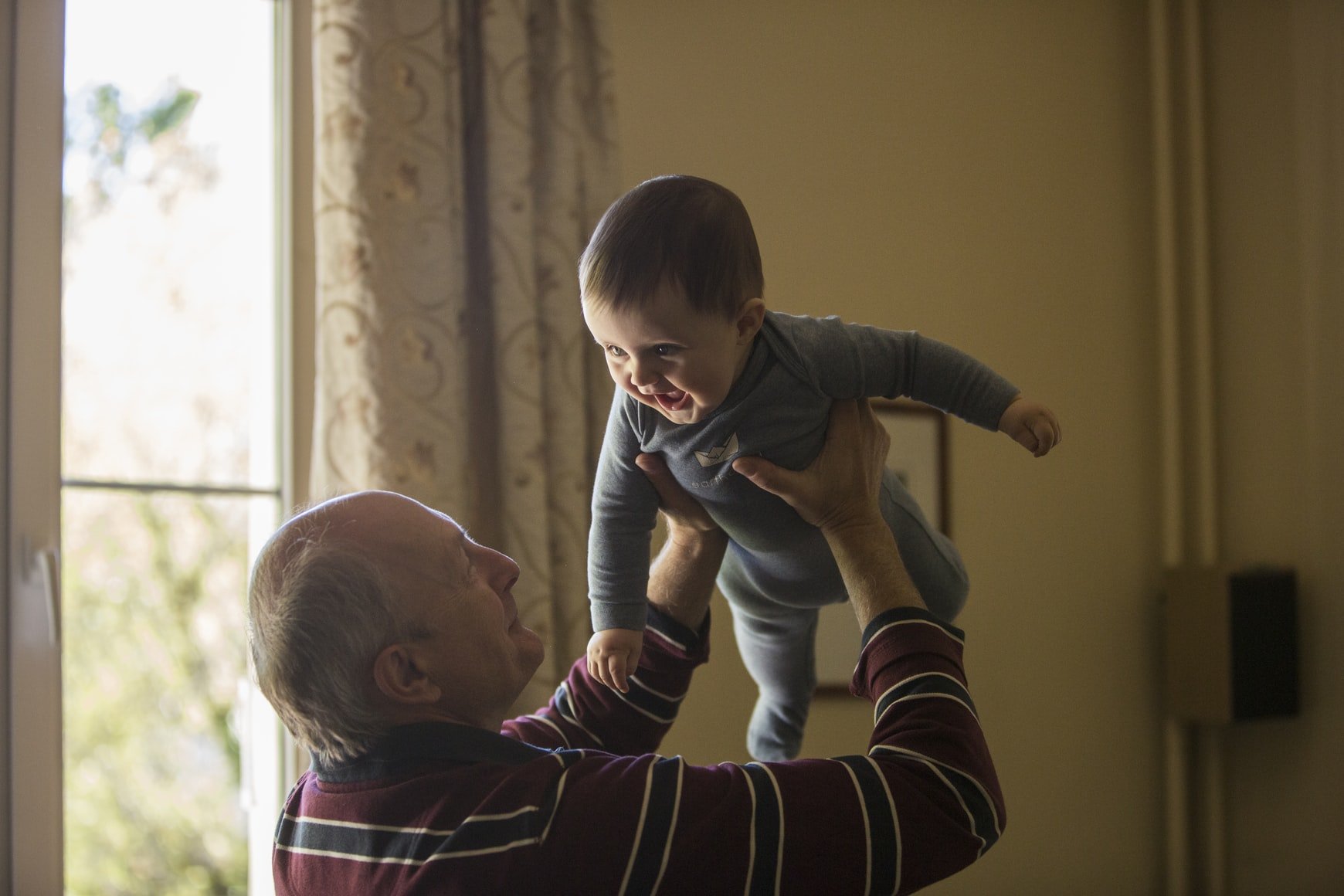 An older man pictured lifting a baby. | Source: Unsplash