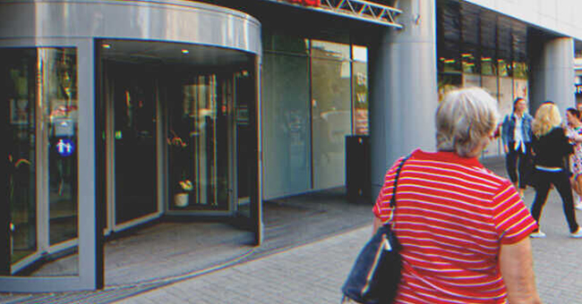 Eine ältere Frau geht an einem Geschäft vorbei | Quelle: Shutterstock