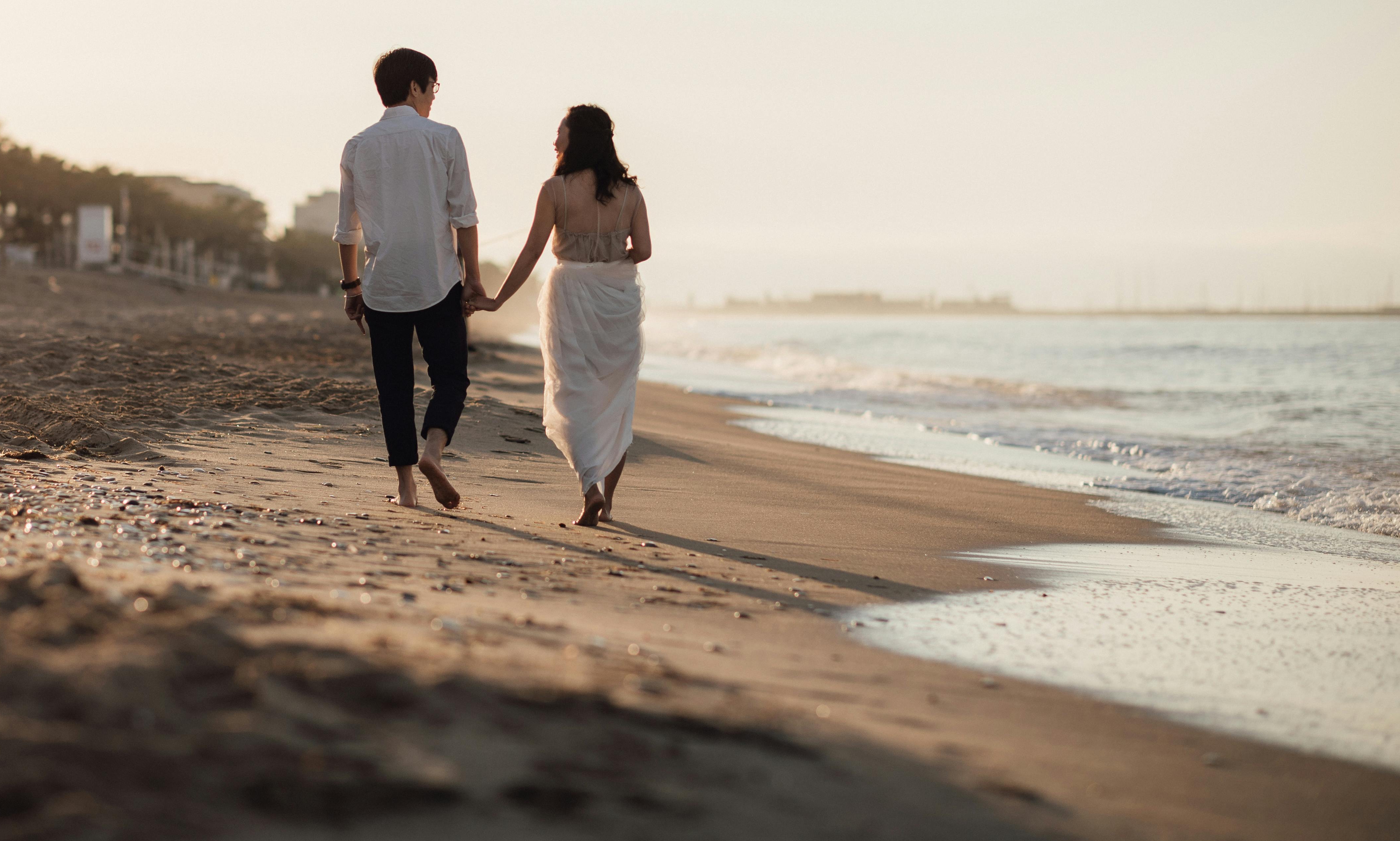 A couple walking hand-in-hand on a beach at sunset | Source: Pexels